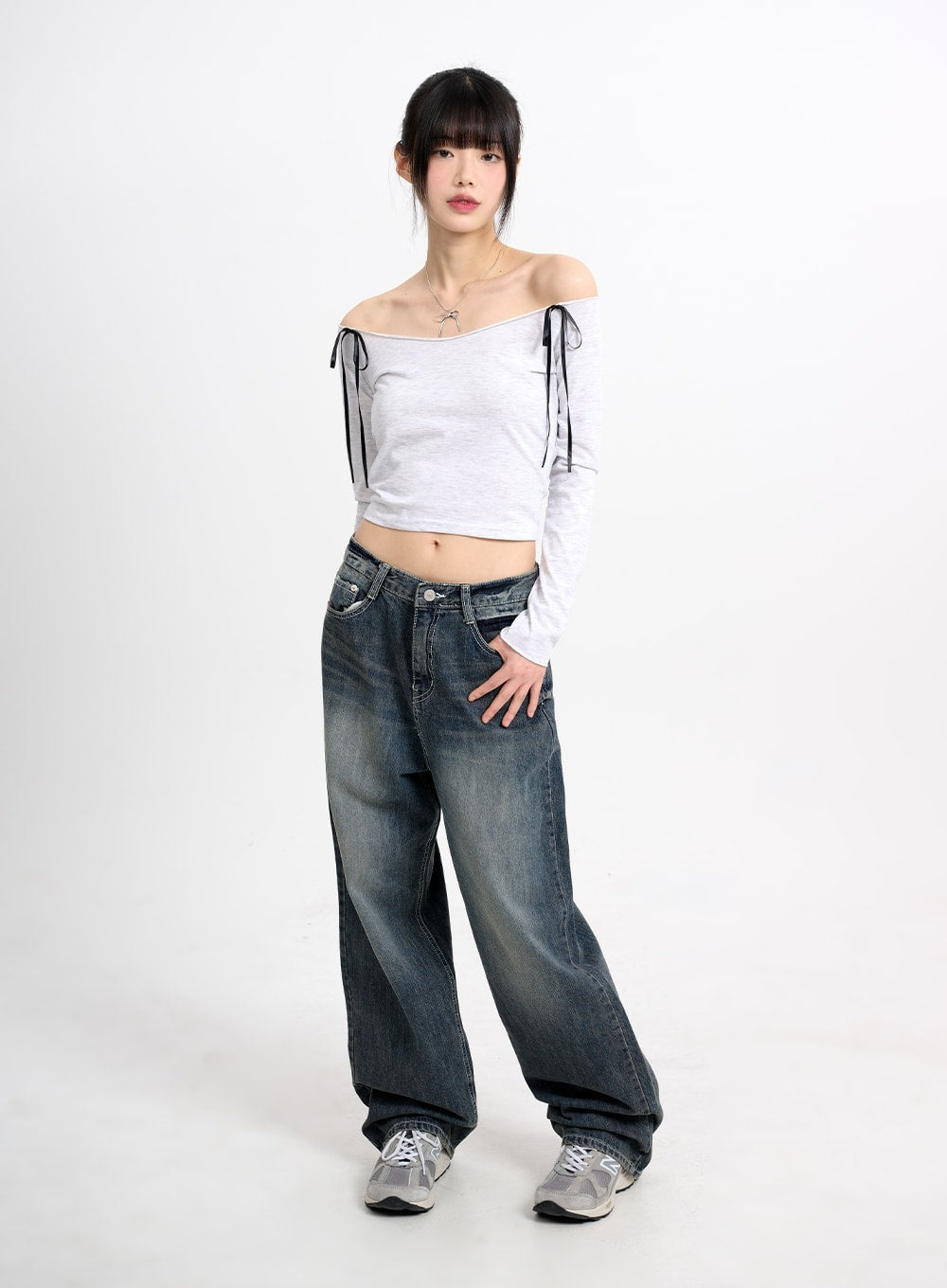 Low Waist Baggy Jeans CM415 in dark blue, full-body front shot on model, low-rise wide-leg silhouette pooling at hem, styled with off-shoulder crop top and grey sneakers.