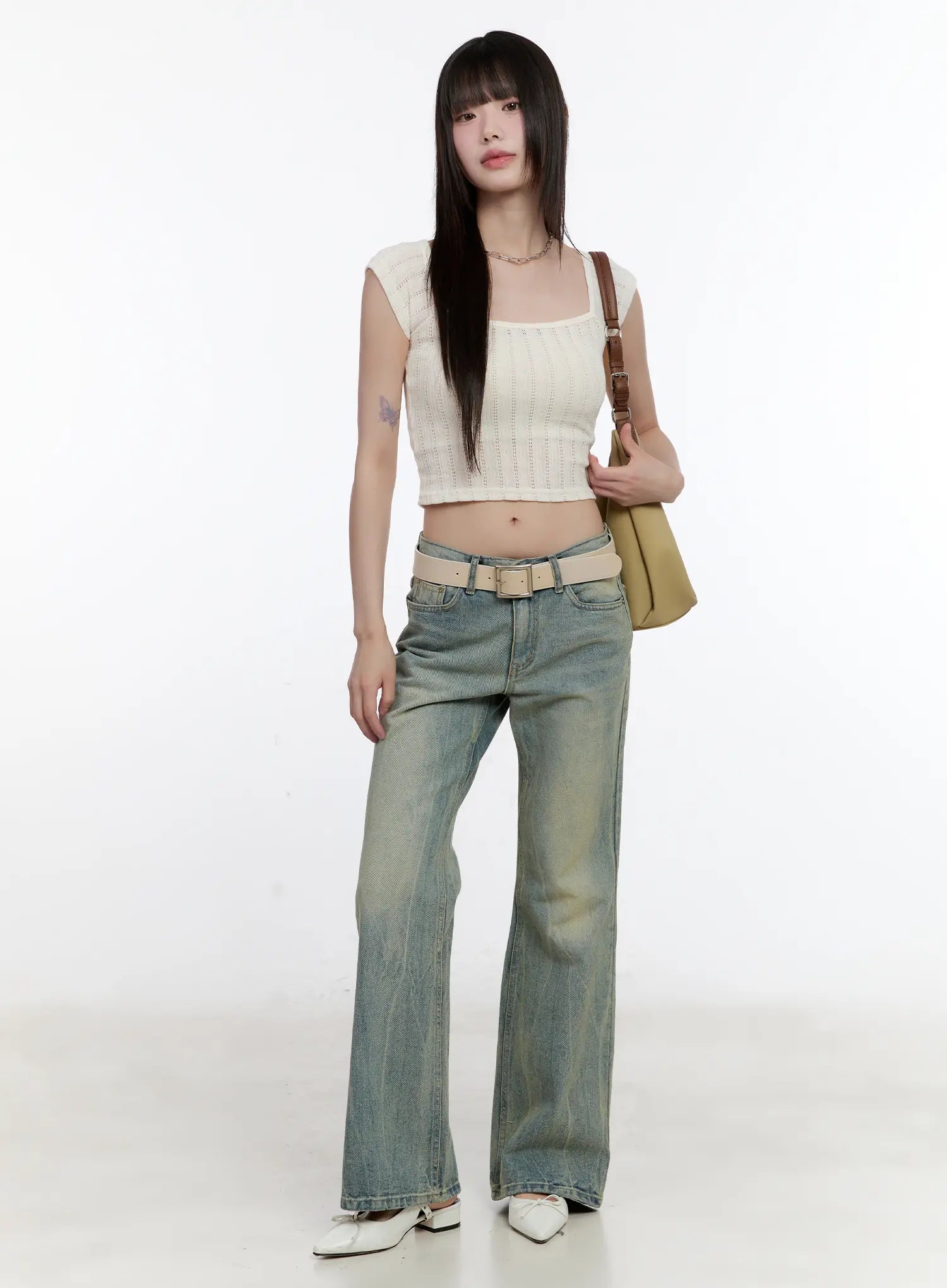 Roa Vintage Blue Flared Denim Jeans CL504 in blue, full-body front shot on model standing straight, washed flared denim with belt, styled with cream knit crop top and olive shoulder bag.