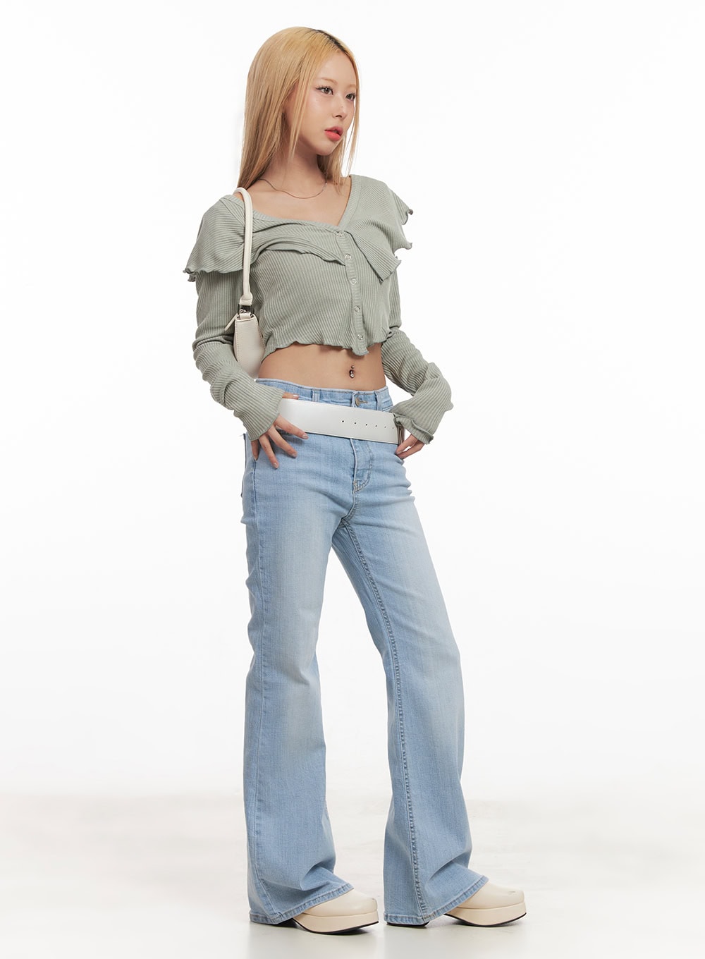 Suzy Slim-Fit Bootcut Jeans CM505 in light blue, full-body side-angle shot on model, slim fit with flared hem, styled with green ruffle crop top, white belt, and shoulder bag.