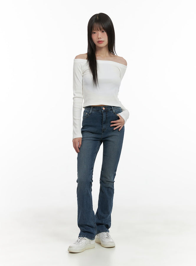 Pixie Slim Washed Bootcut Jeans CG427 in blue, full-body front shot on model, slim fit washed denim with gentle bootcut hem, styled with white off-shoulder crop top and white sneakers.