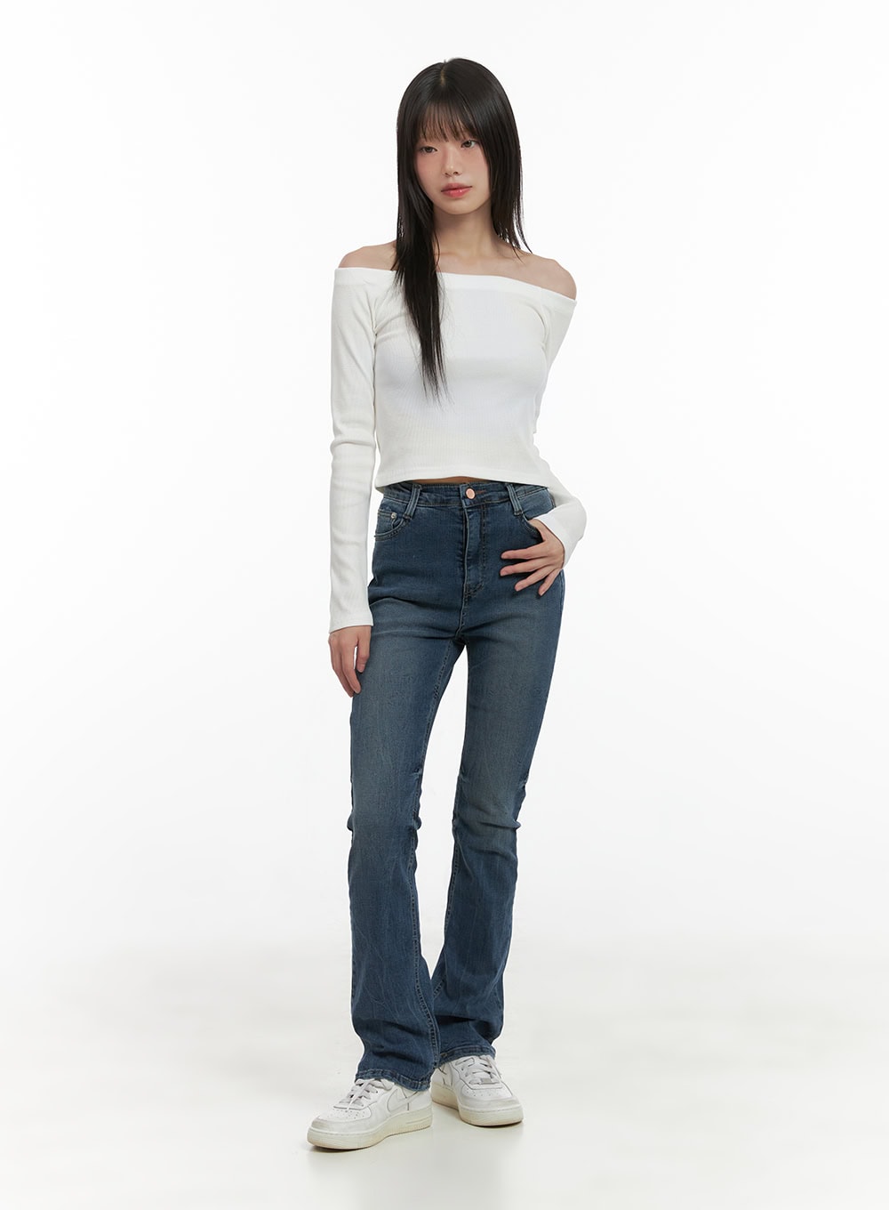 Pixie Slim Washed Bootcut Jeans CG427 in blue, full-body front shot on model, slim fit washed denim with gentle bootcut hem, styled with white off-shoulder crop top and white sneakers.