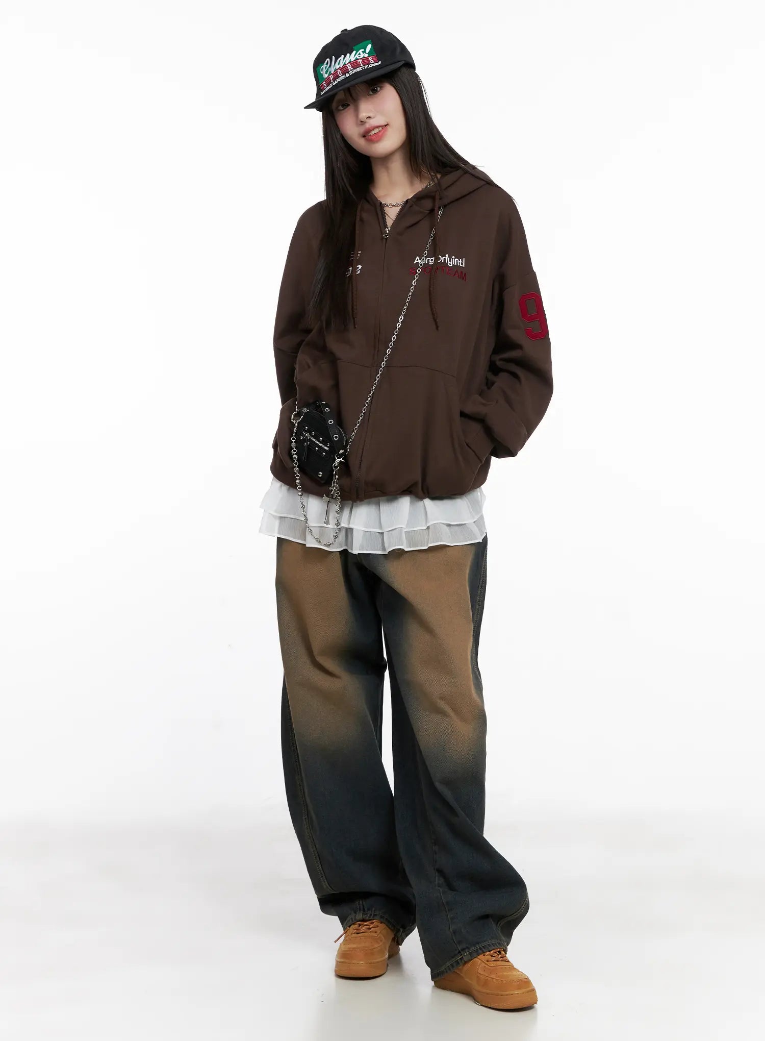 Jaycee Vintage Wash Baggy Jeans CG519 in dark blue, full-body editorial shot on model, styled with brown graphic hoodie, layered white top, cap, and chain bag.