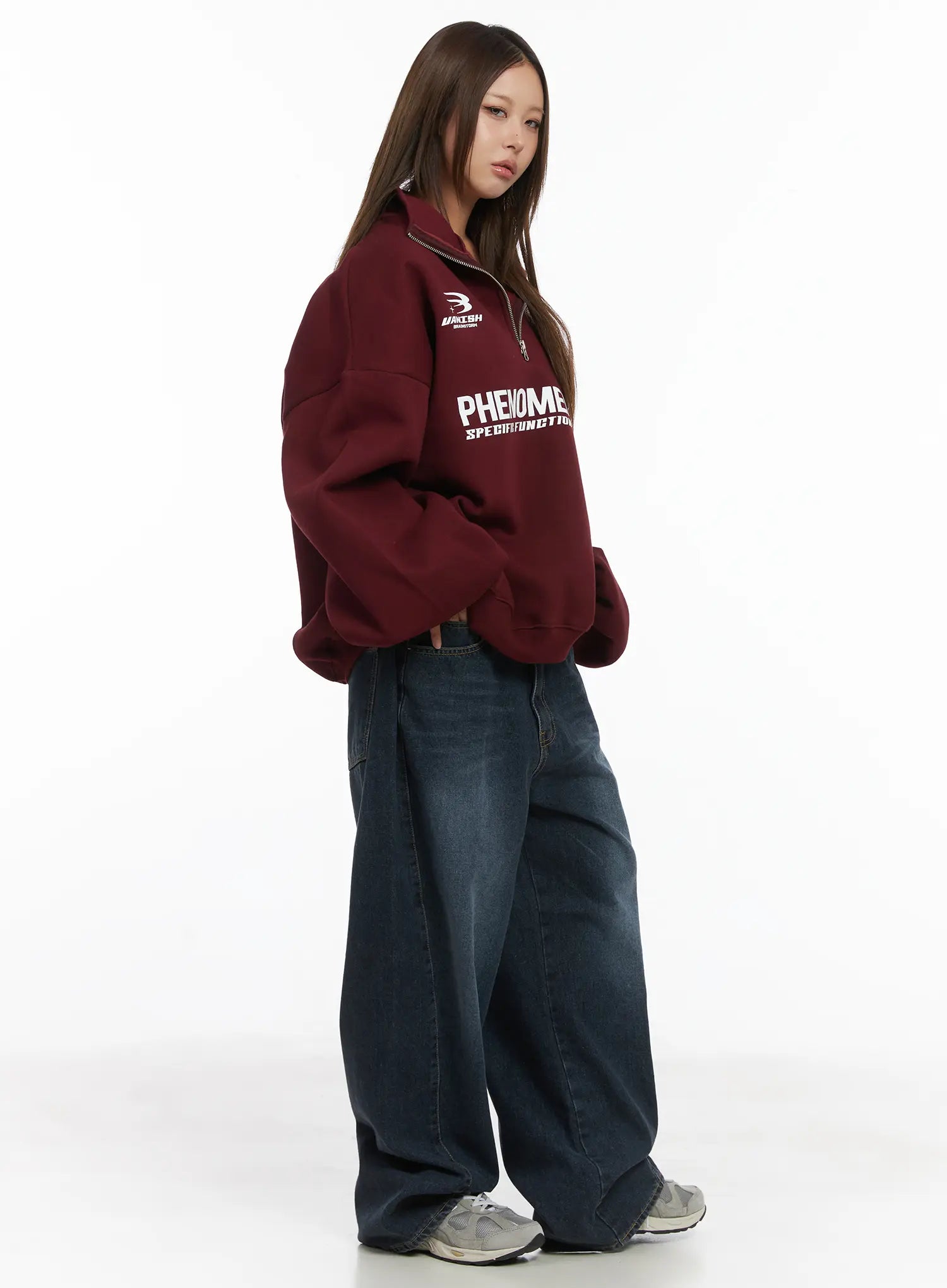 Everly Wide Leg Jeans CJ513 in dark blue, 3/4 side view on model, long wide-leg silhouette with washed finish, styled with burgundy graphic half-zip sweatshirt and grey sneakers.