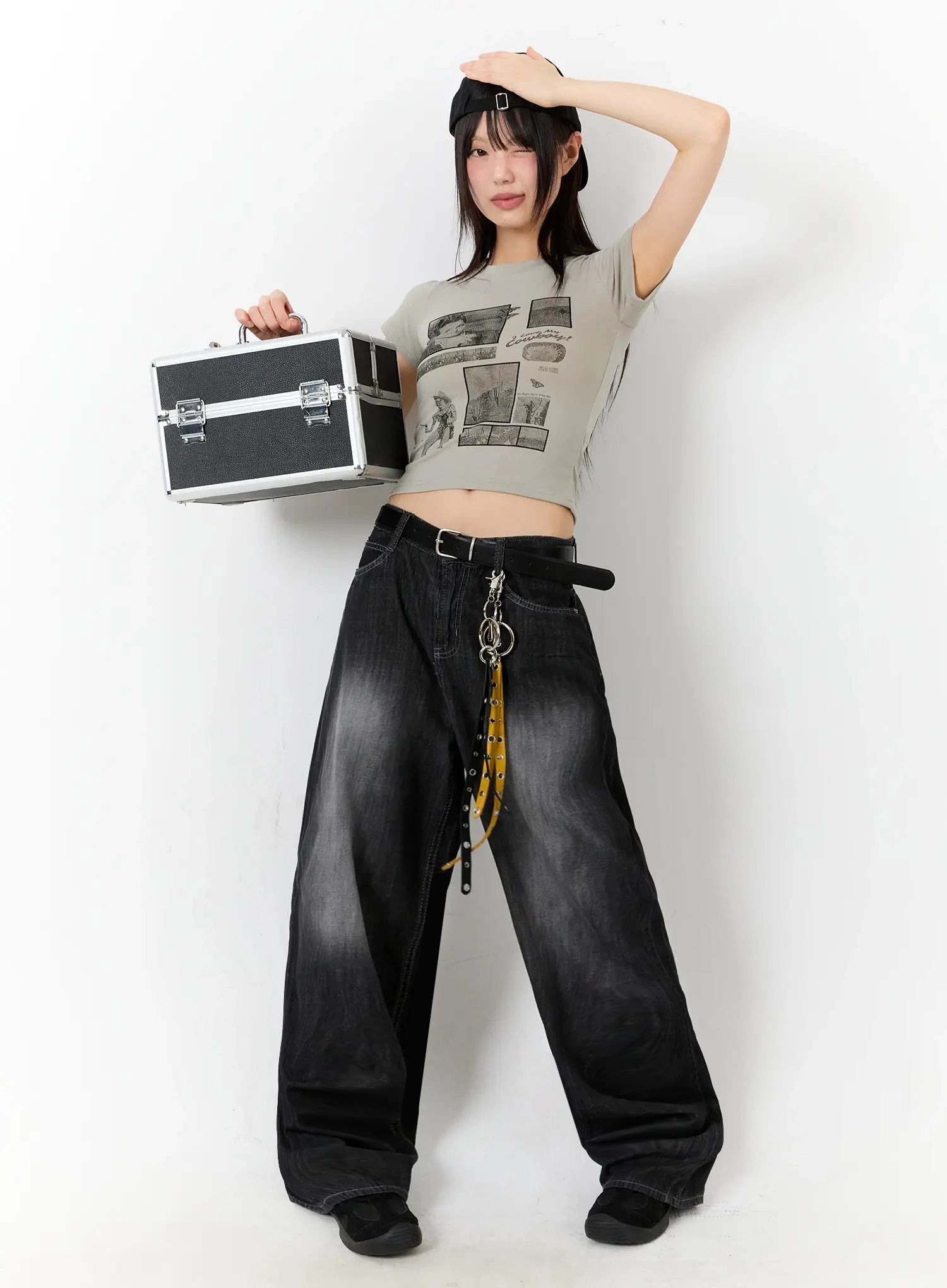 Wendy Washed Wide-Leg Jeans IU524 in black, full-body editorial shot on model with arms raised, belted waist with chain accessory, paired with grey graphic crop tee and cap.