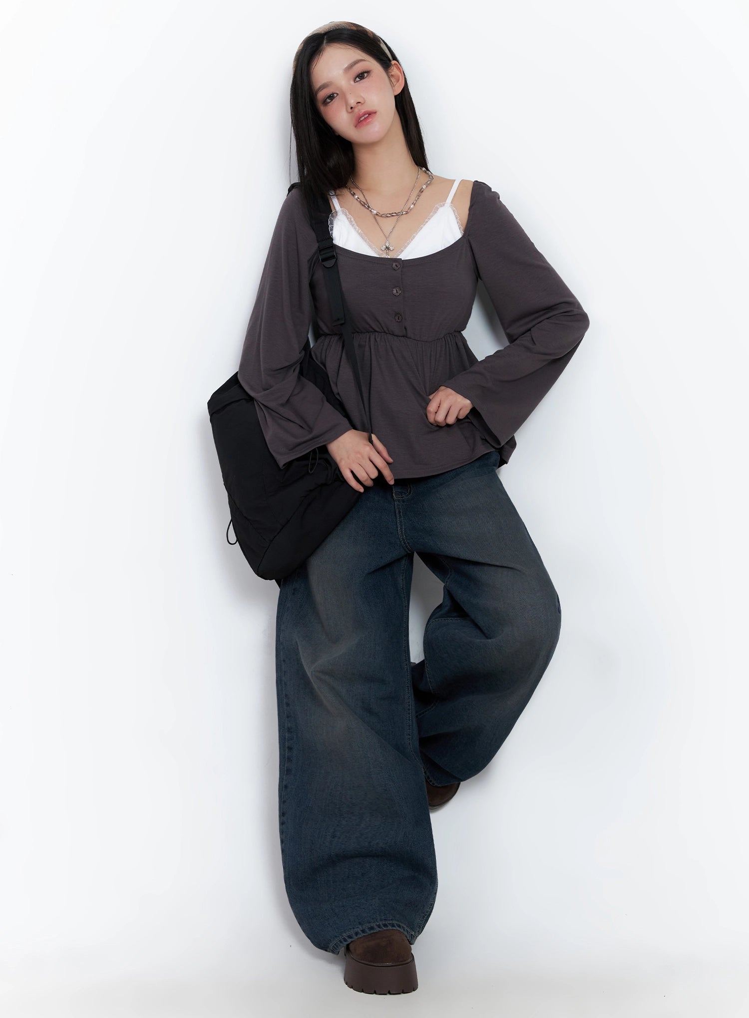 Adelyn Washed Baggy Jeans IS525 in dark blue, full-body styled shot on model leaning against wall, wide-leg washed denim paired with charcoal peplum top and black backpack.