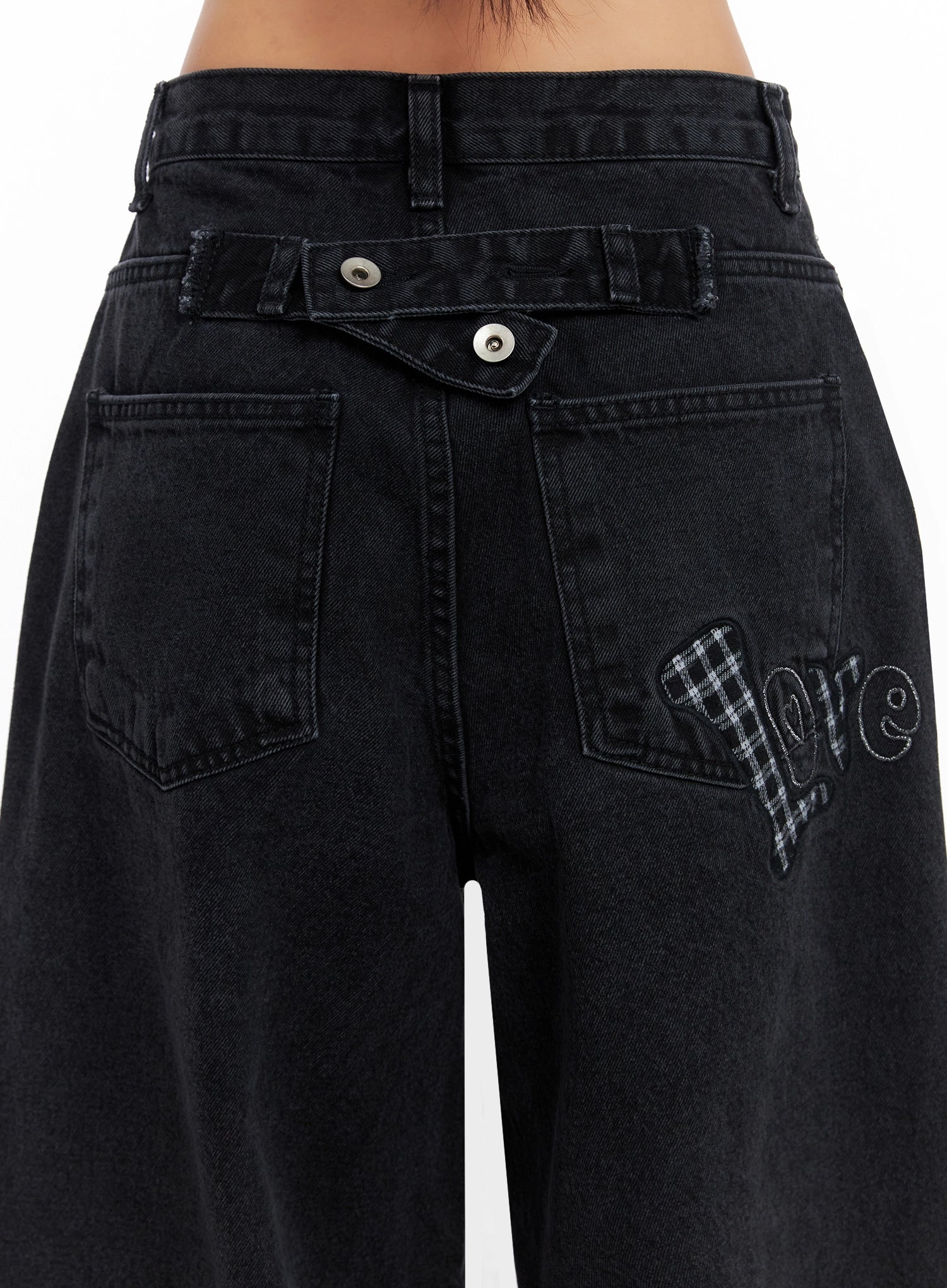 Sunwoo Embroidered Wide Leg Jeans IG528 in black, close-up back waistband detail on model, showing double-button fly, back pockets and gingham heart 'love' lettering patch embroidery.