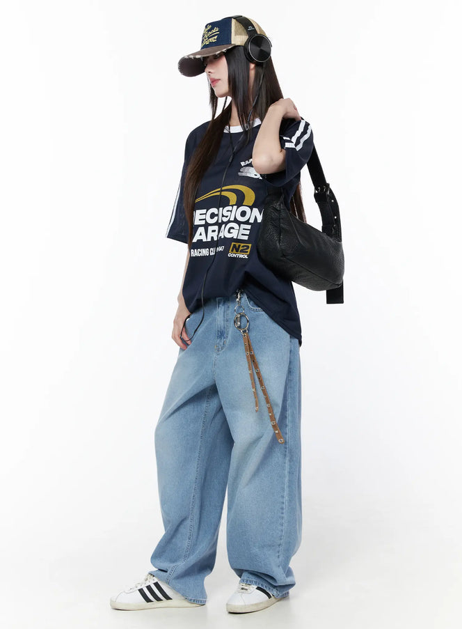 Nella Wide Leg Jeans CU519 in blue, full-body styled shot on model, light-wash wide leg denim paired with navy graphic tee, cap, and black shoulder bag.