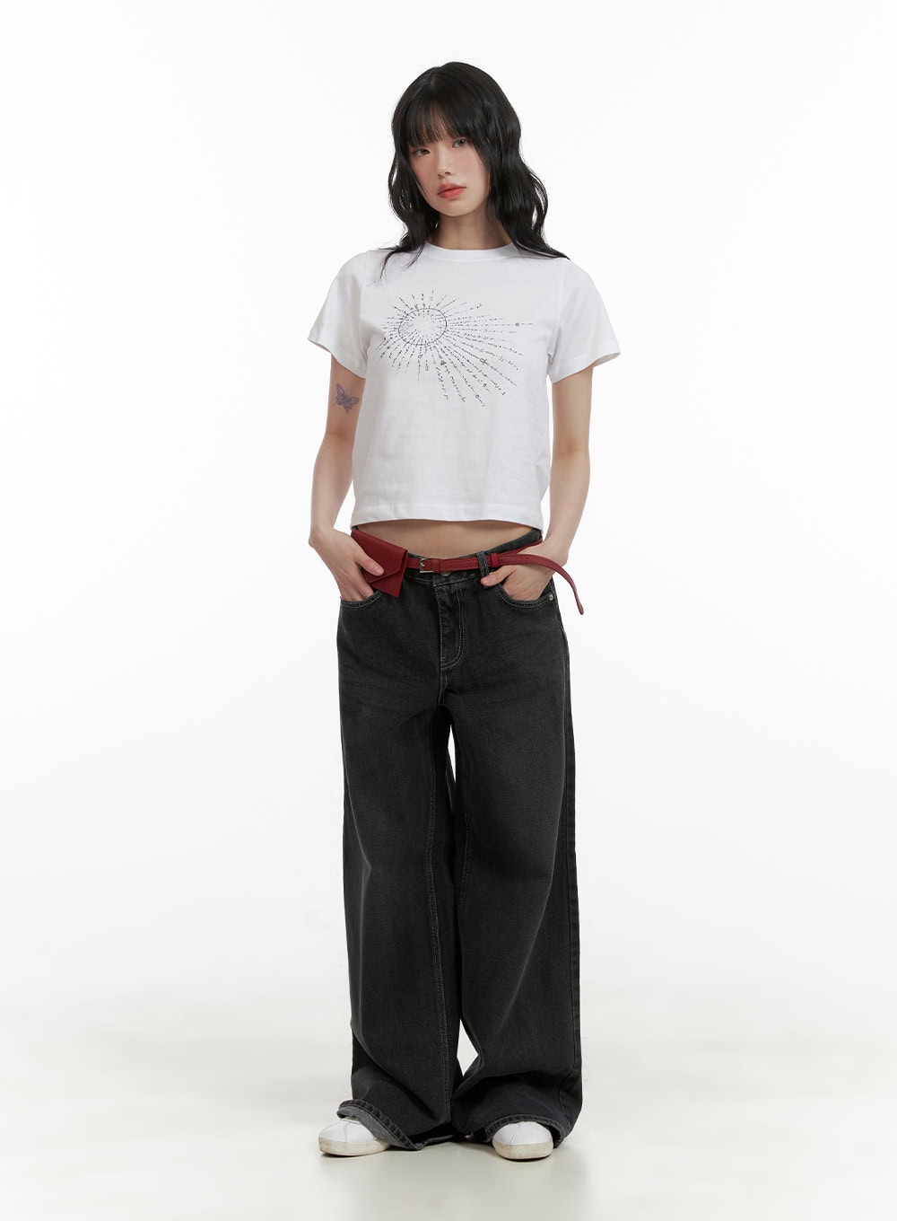 Low Rise Baggy Jeans CU410 in black, full-body front view on model, wide-leg washed denim, paired with white graphic crop tee, red belt, and white sneakers.