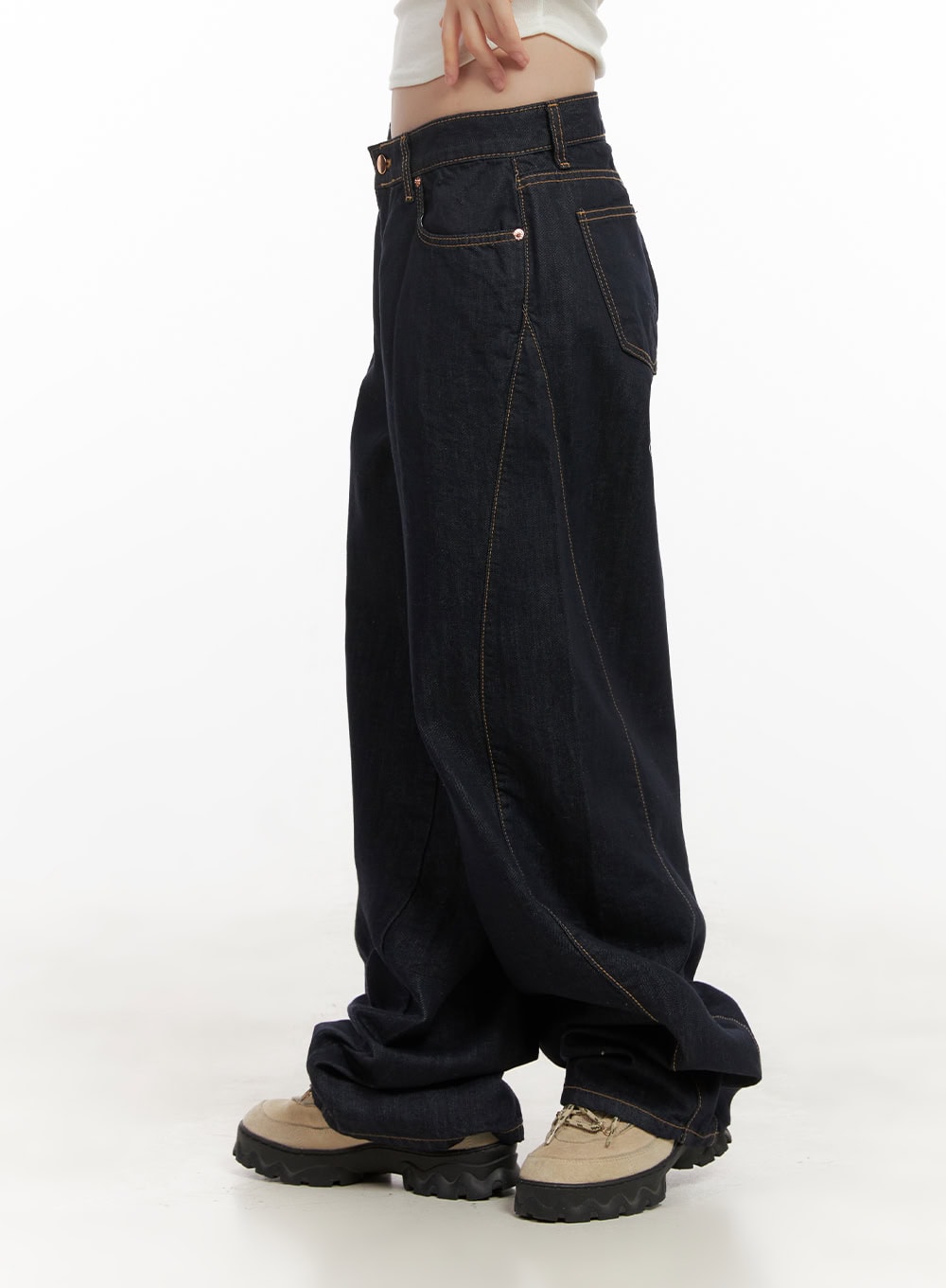Fernanda Balloon-Fit Baggy Jeans CJ502 in dark blue, side view on model, wide balloon-fit cotton denim with contrast topstitching and low waist, extra-long hem bunching at ankle over chunky sneakers.