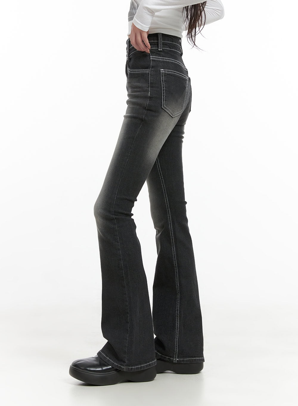 Gigi Two-Button Slim Bootcut Jeans CG421 in black, side view on model, high-waist slim fit with visible contrast stitching and back pocket detail, bootcut flare hem over black chunky shoes.