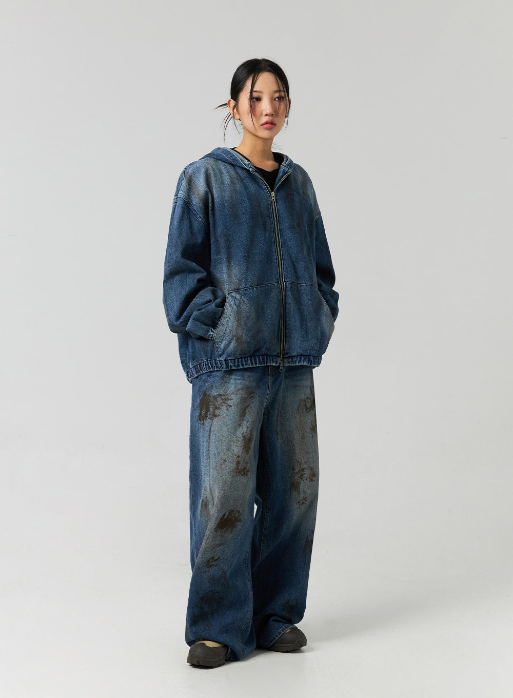 Street-Style Wide Fit Washed Jeans CO323 in Blue, full-body slight side angle on model in denim zip hoodie, wide fit cotton denim with all-over brown washed stain detailing.