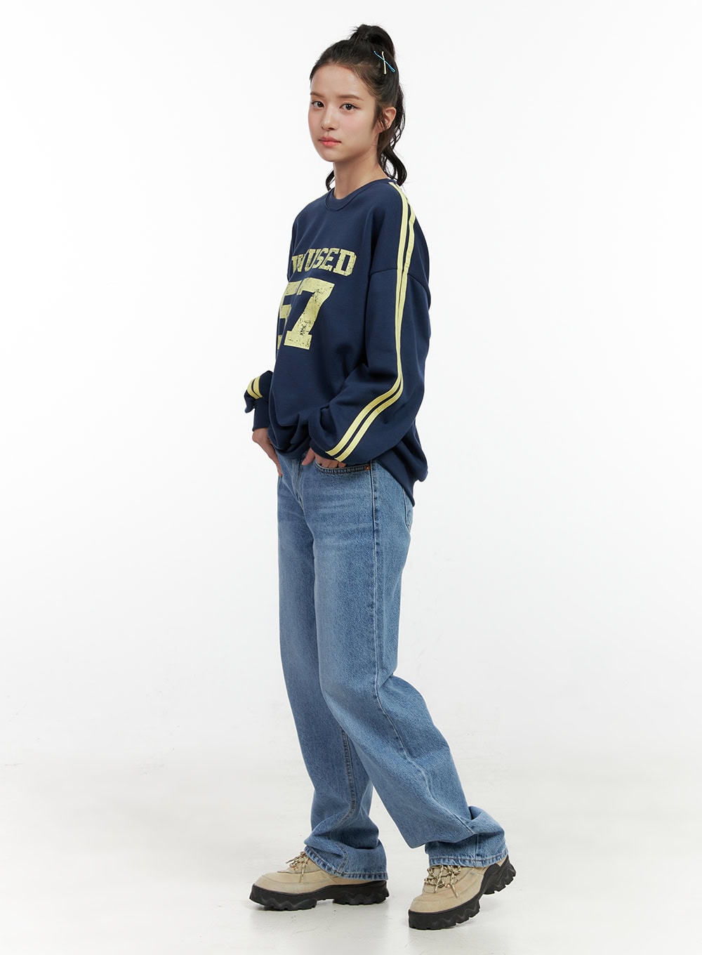 Carly Cloud Wide-Leg Jeans ON404 in blue, side full-body shot on model mid-stride, wide-leg washed denim silhouette with loose straight fall, paired with navy varsity sweatshirt and sneakers.