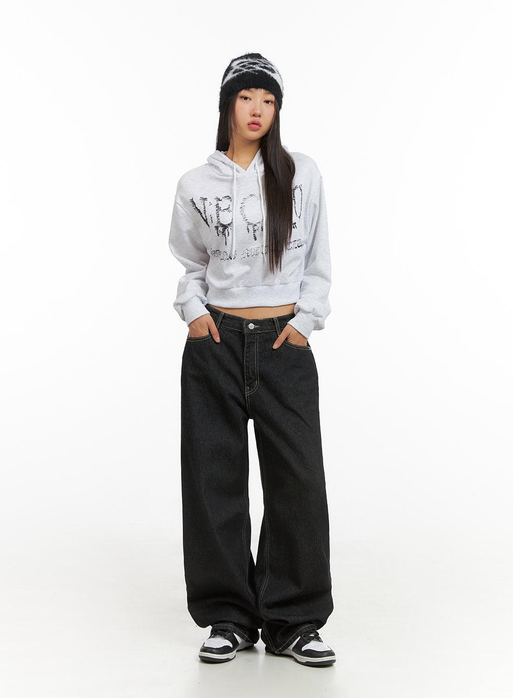 Clover Stitched Baggy Jeans IS402 in black, full front view on model, wide-leg low-rise denim with contrast topstitching, paired with grey graphic crop hoodie, beanie, and sneakers.