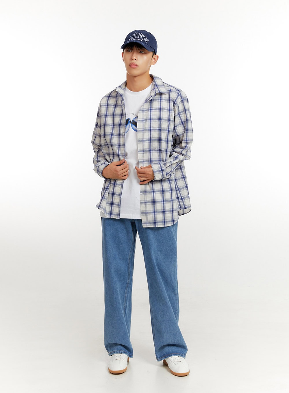 Men's Baggy Jeans (Blue) IU427 in blue, full-body front shot on model adjusting plaid overshirt, relaxed baggy fit with wide leg, paired with white tee and cap.