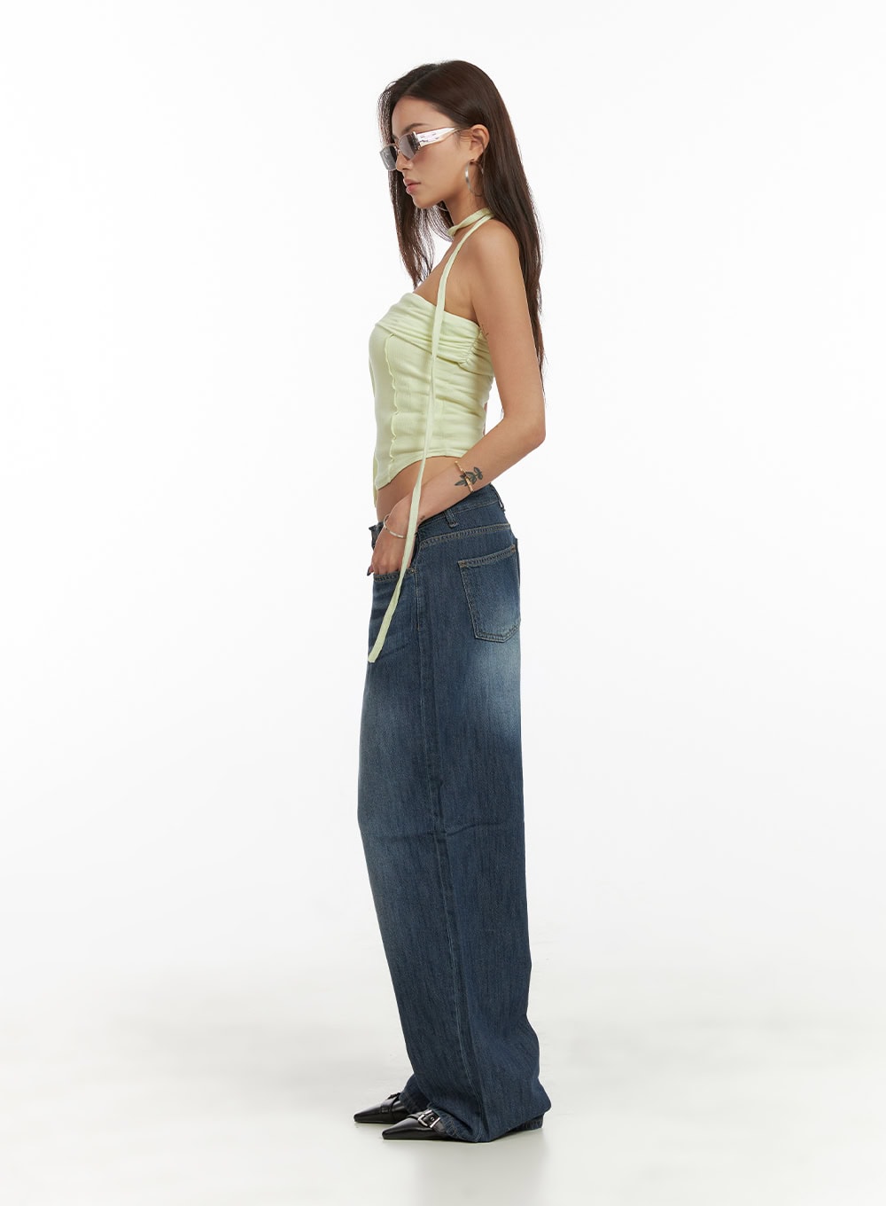Low Rise Wide Fit Baggy Jeans CY431 in dark blue, full-body side view on model, washed denim baggy silhouette with voluminous wide leg, styled with lime green halter top and black buckle flats.
