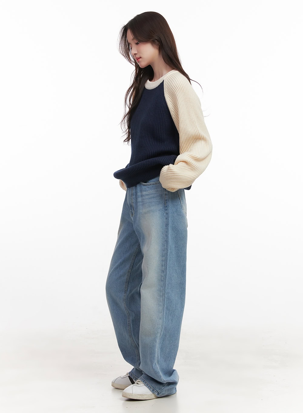 Kelly Washed Baggy Jeans CJ514 in light blue, side view on model looking down, washed baggy denim with wide leg and faded finish, styled with colorblock knit top and white sneakers.