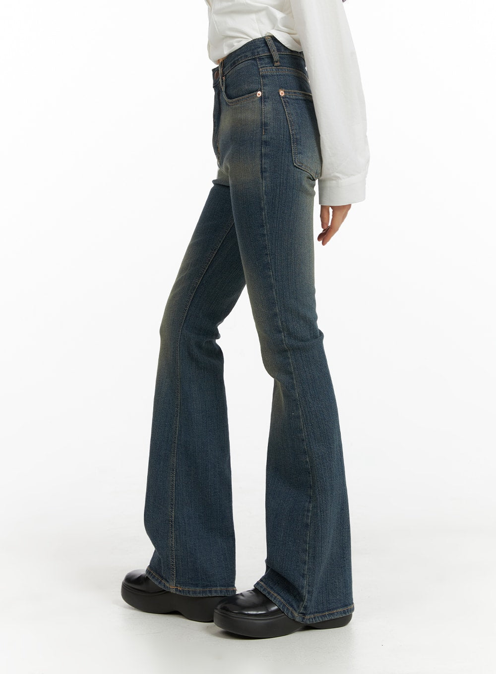 Washed Flared Jeans CM413 in blue, side view on model, showcasing slim high-rise fit and flared hem with vintage washed cotton-spandex denim, paired with white top.