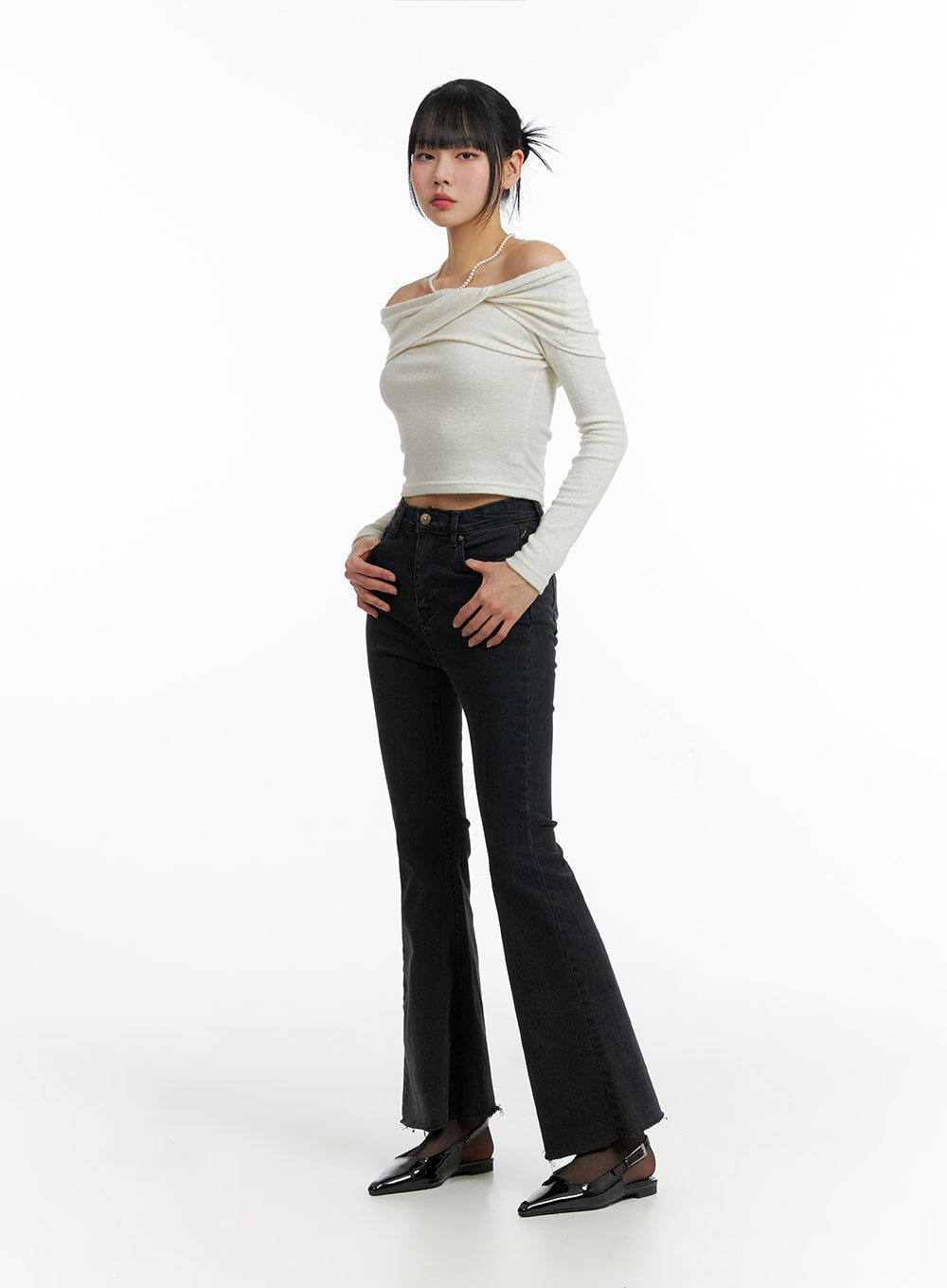 Mid Waist Button Flared Jeans IF402 in dark grey, front full-body shot on model, mid-rise waist with gold button closure, flared leg and raw-cut hem, styled with cream off-shoulder top and black flats.