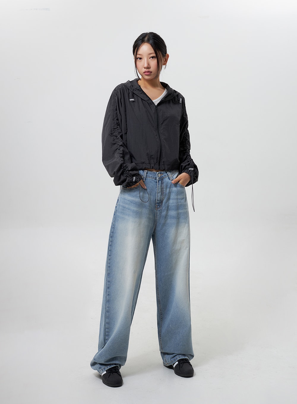 Low Rise Baggy Jeans CY324 in light blue, full-length front view on model standing upright, wide-fit faded denim, hands in pockets, styled with black cropped hooded jacket.
