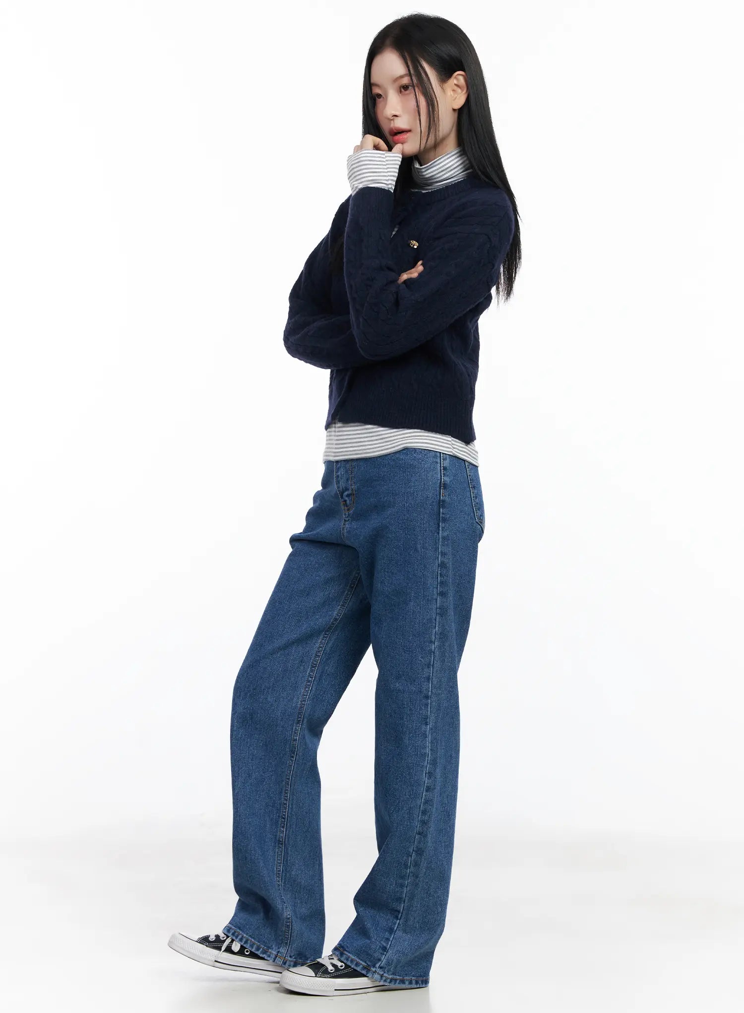 Aila Relaxed Fit Jeans CJ519 in blue, side view on model, long wide-leg washed cotton denim, layered with navy cardigan and striped turtleneck, Converse sneakers.