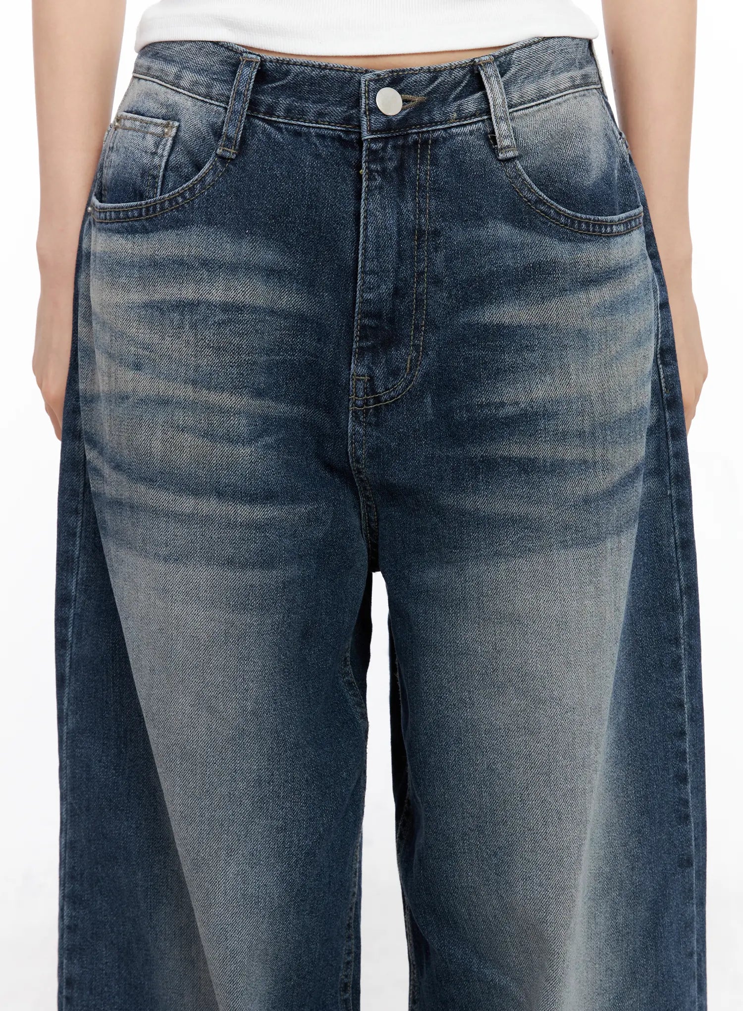Aisha Washed Baggy Jeans CC1109 in mid blue, waist-level close-up on model, showing front pockets, silver button, and vintage washed fading detail on wide-fit cotton denim.