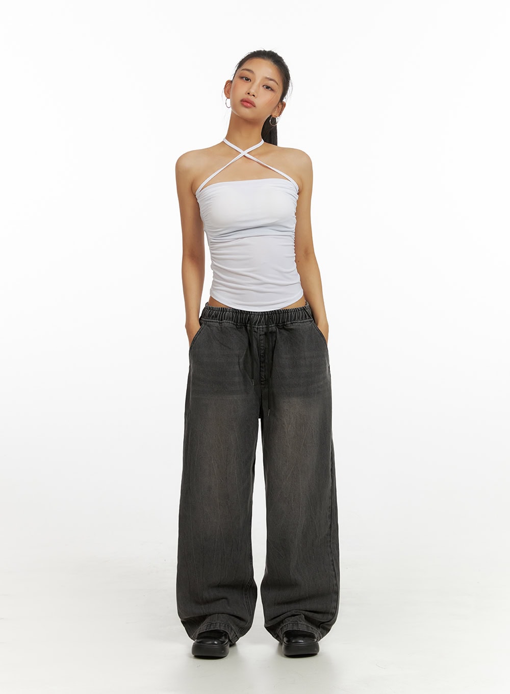 Banding Baggy Jeans IU412 in washed black, front full-body shot on model, hands in pockets, relaxed wide-fit denim with elastic banded waist and drawstring, styled with white halter top.