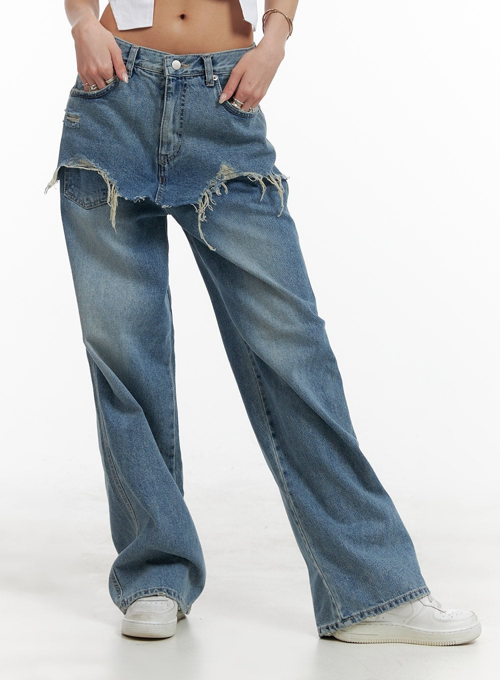 Layered Wide Leg Jeans CA430 in Blue, front waist-to-hem close-up on model, showing frayed destroyed skirt overlay detail and washed denim texture, wide fit with hands in pockets.