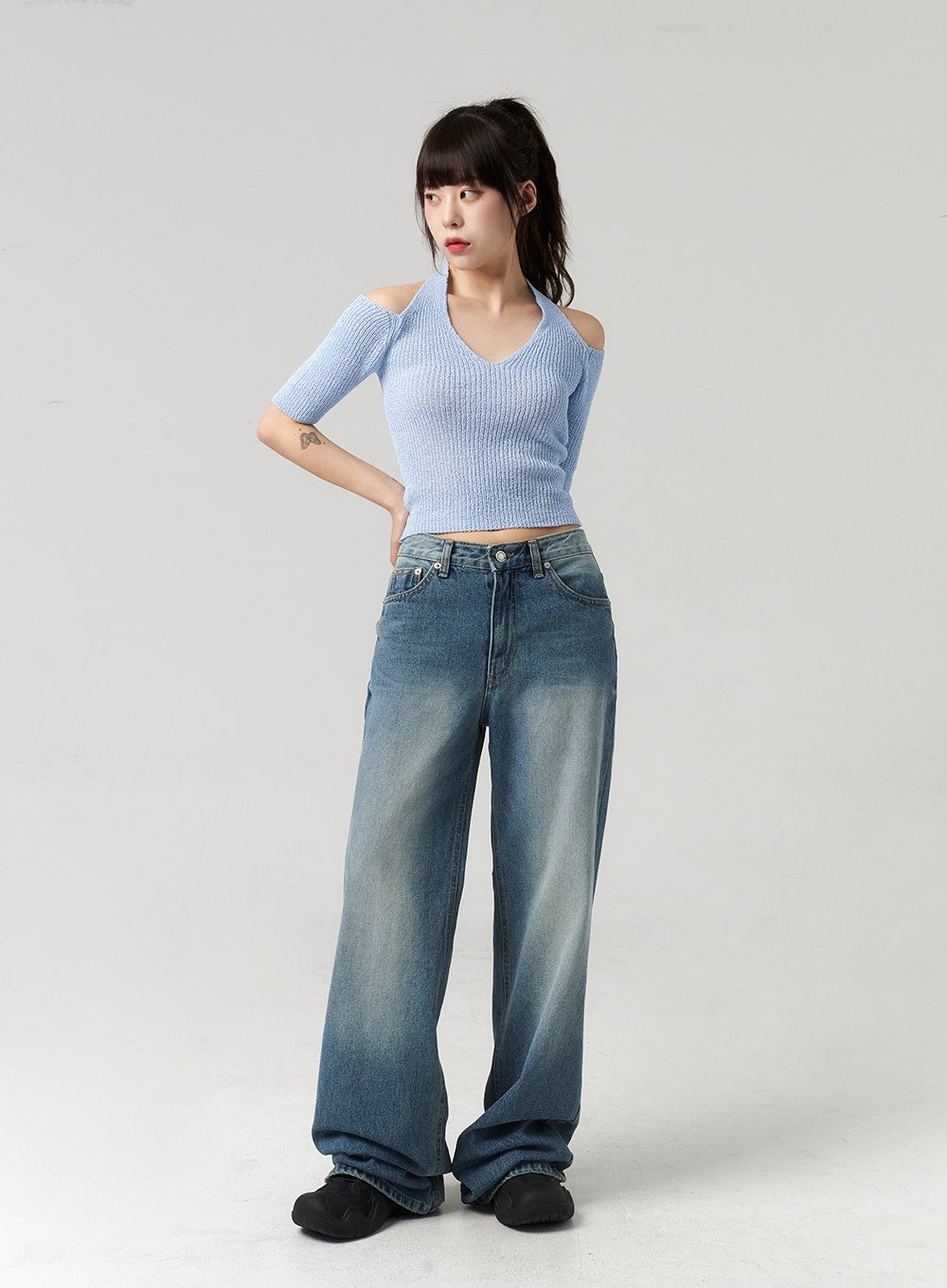 Mid-Wash Baggy Jeans CL312 in mid-wash blue, three-quarter front view on model turning slightly, wide-fit denim with washed gradient, styled with blue halter crop knit.