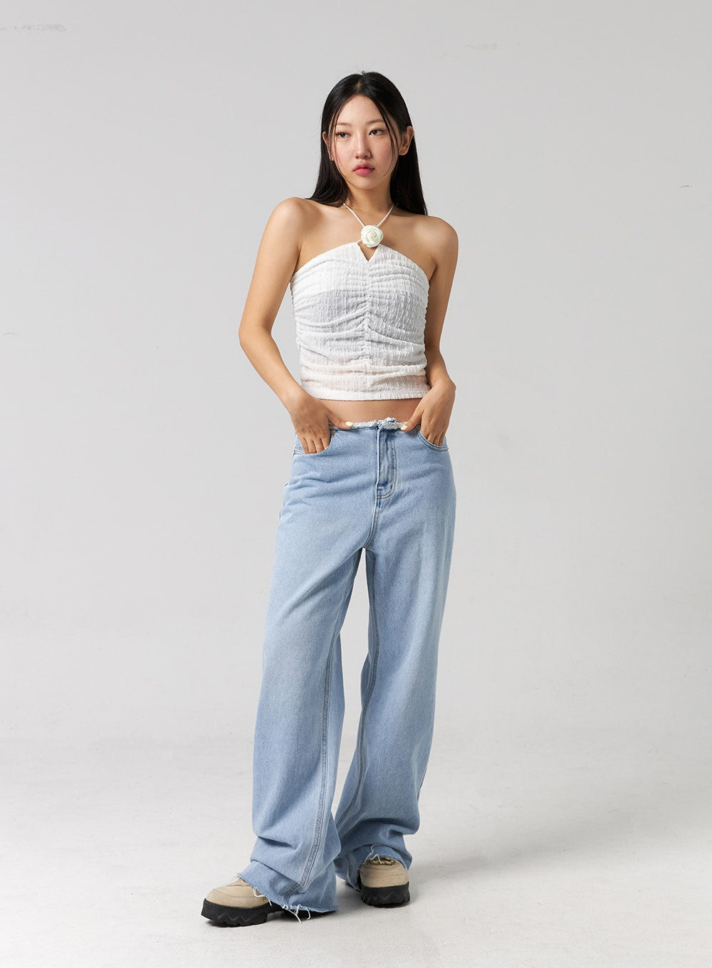 Cut Waist Wide Leg Jeans CG323 in light blue, straight-on full-body front shot on model, hands in pockets, wide-fit cotton denim with frayed waist, styled with white halter top.