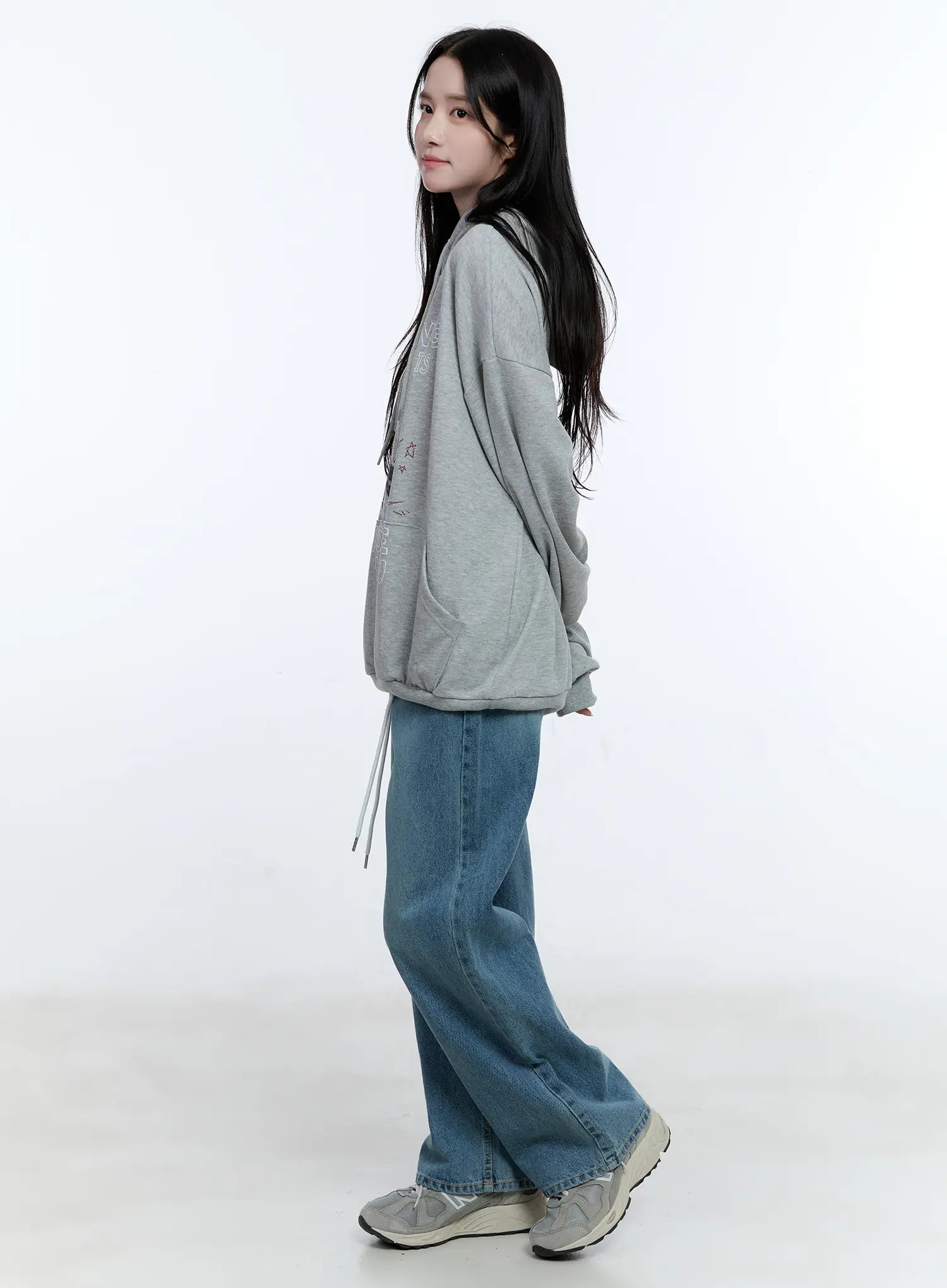 High-Waist Wide-Leg Drawstring Jeans CG513 in blue, side view on model walking, wide-leg washed cotton denim with dangling white drawstring, paired with grey hoodie and chunky sneakers.