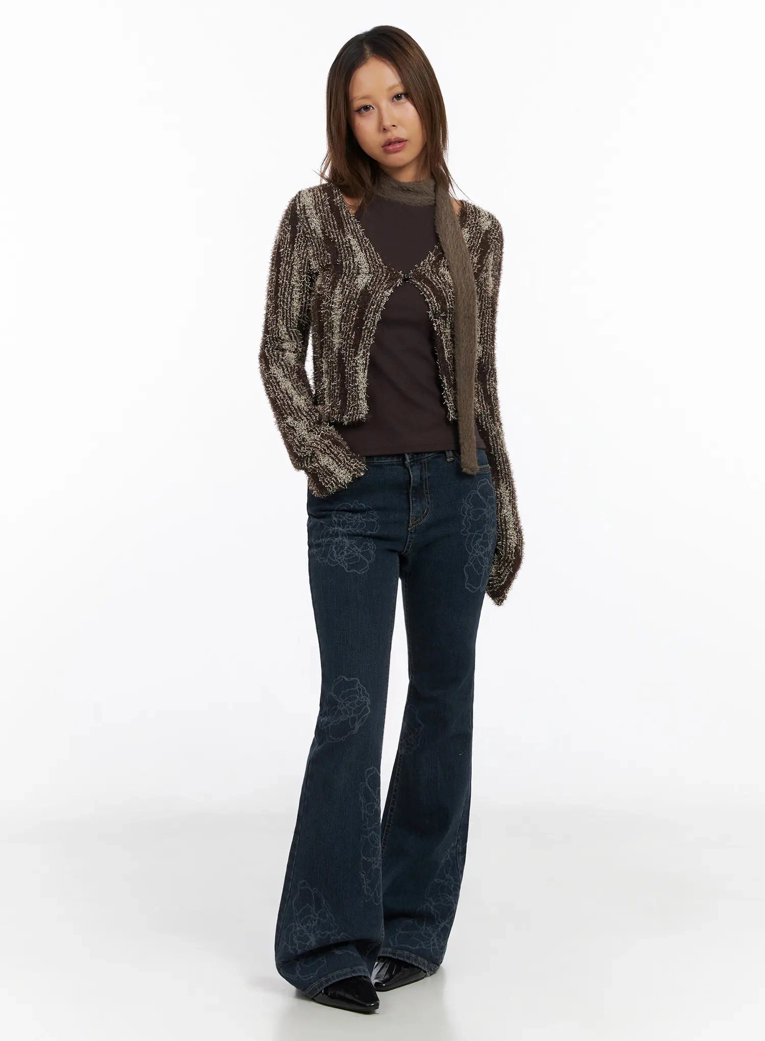 Amari Floral Embriodered Bootcut Jeans IN528 in dark blue, three-quarter front shot on model, floral embroidered bootcut flare, paired with open-front marled knit cardigan and brown halter top, black patent boots.