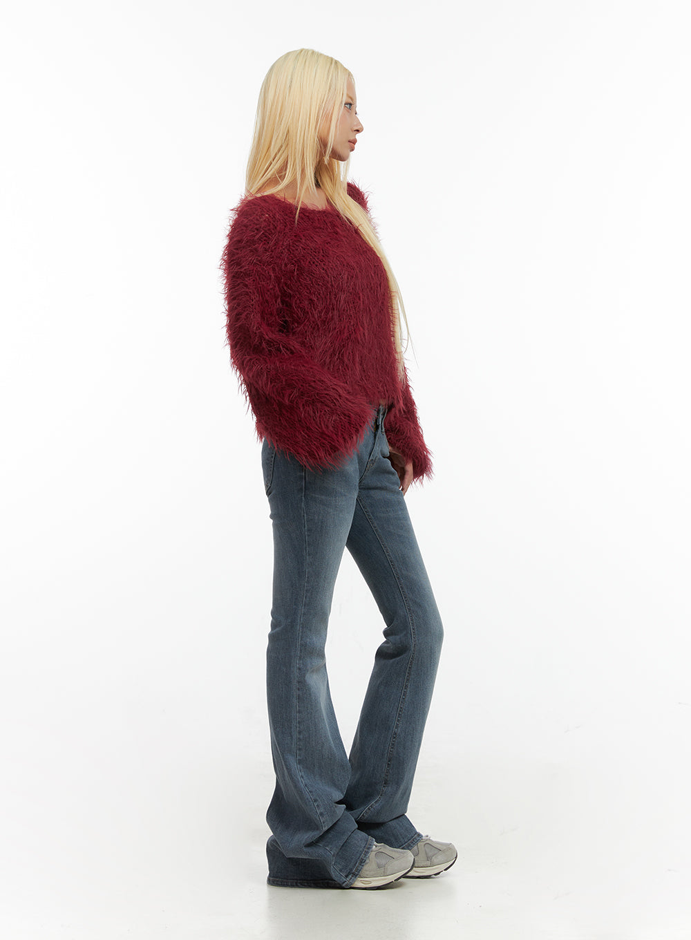 Liv Washed Denim Low Waist Bootcut Jeans CO414 in blue, side view on model, slim-fit bootcut flare leg visible, low waist, washed cotton denim, paired with red fluffy sweater and sneakers.