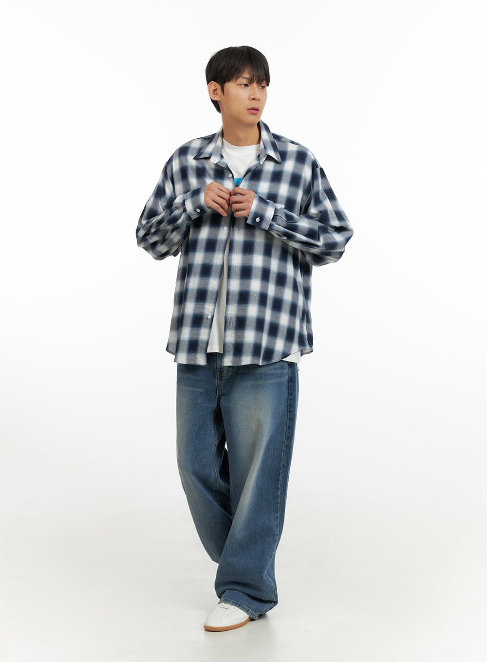 Men's Solid Baggy Jeans IU419 in blue, front three-quarter on model with relaxed pose, wide baggy leg and subtle whiskering, styled with plaid overshirt and white sneakers.