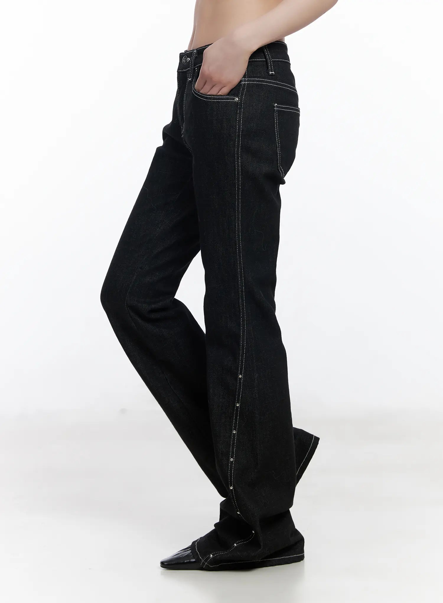 Dahy Stylish High-Waisted Bootcut Jeans CJ526 in black, side view on model, hand in pocket, showing slim thigh to bootcut flare with contrast stitch and silver stud side seam, patent toe shoes.