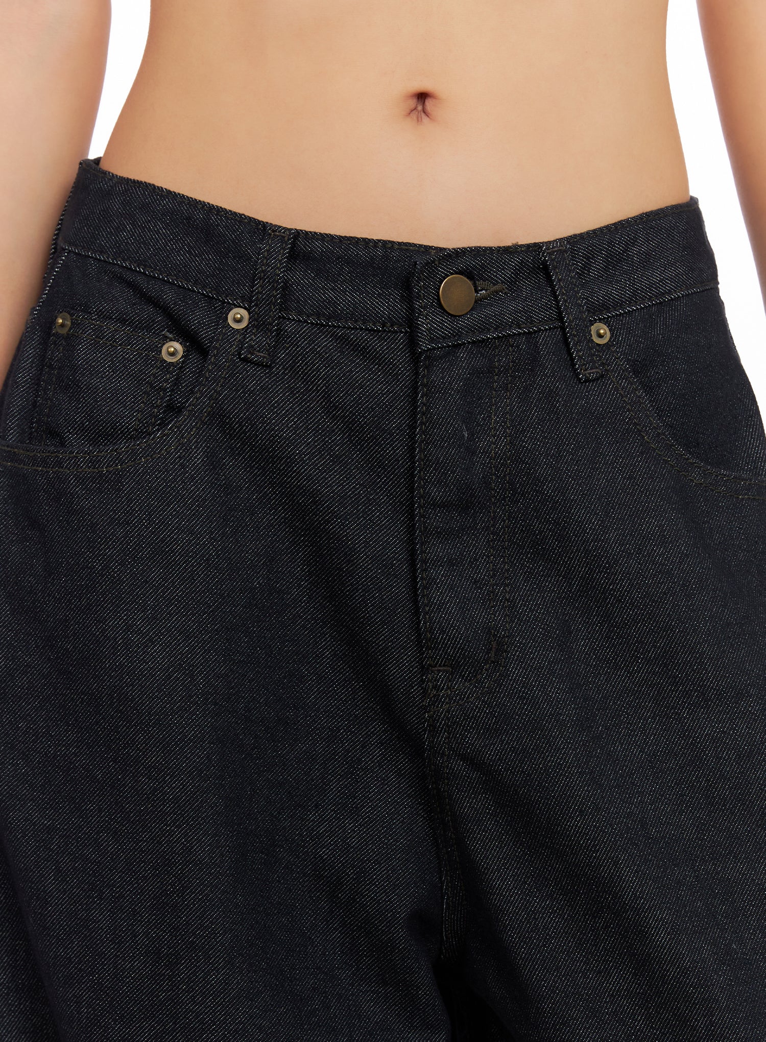 Miller Balloon Baggy Jeans CO515 in dark blue, close-up detail of waistband on model, low-rise fit, brass button closure, front coin pockets, raw denim texture visible.