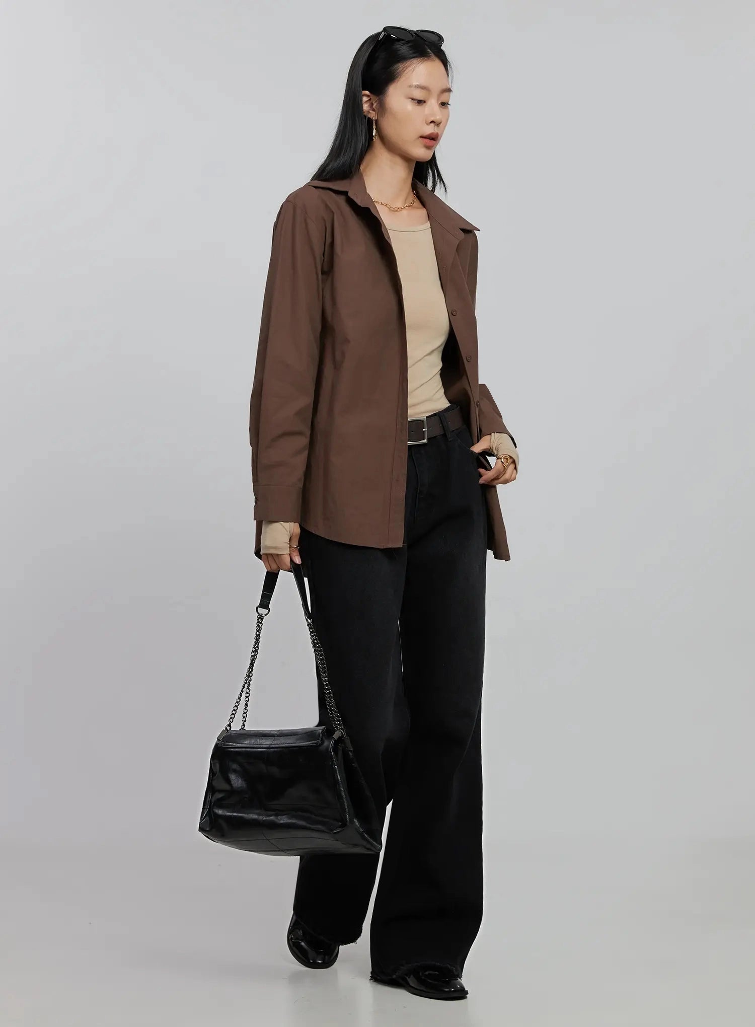 Imani Wide-Leg Flared Jeans ID516 in black, three-quarter side view on model, layered with brown overshirt and beige top, dark belt, black chain shoulder bag, wide-leg cotton denim.