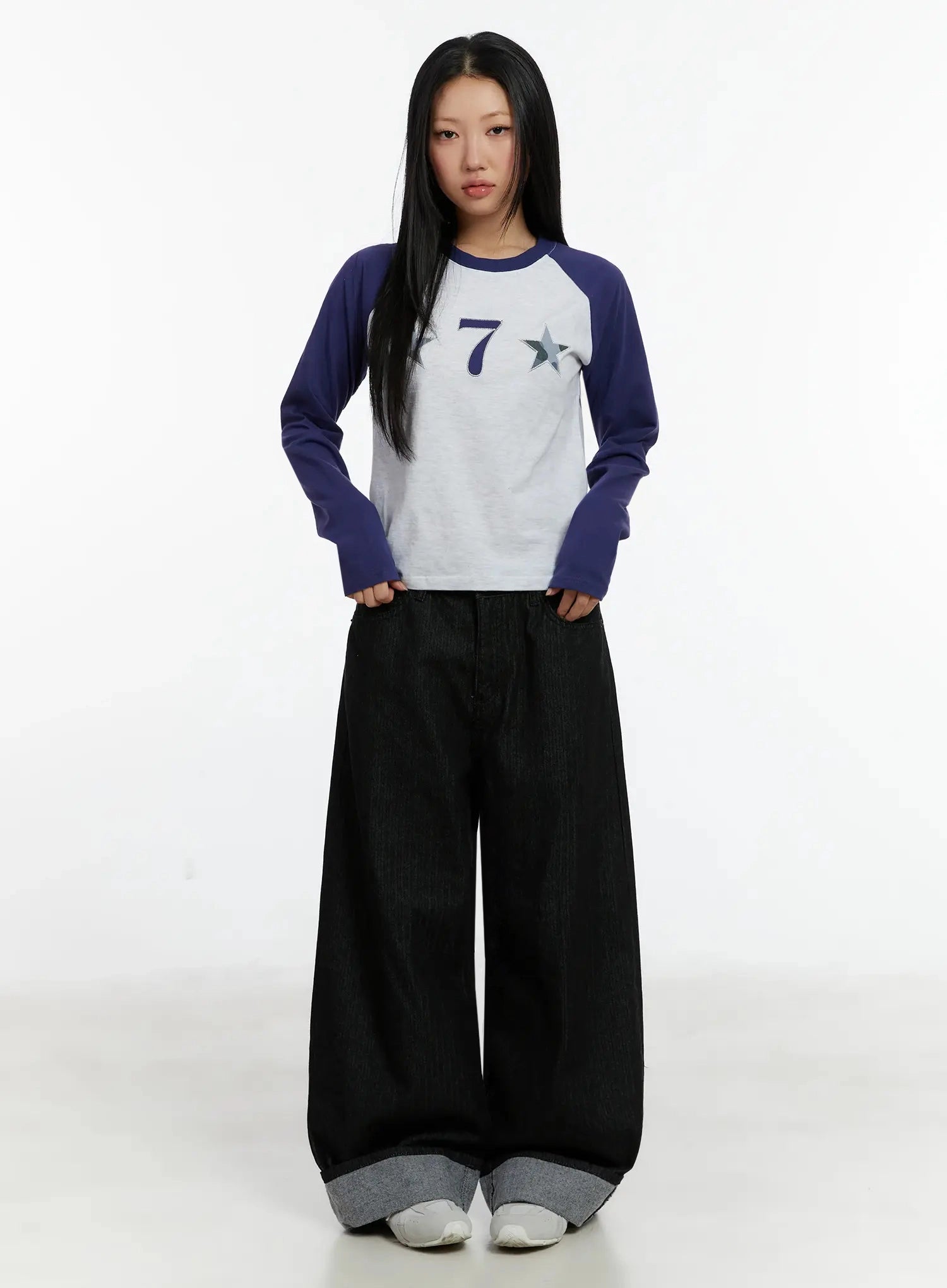 Amyra Baggy Striped Jeans ID525 in black, full-body front view on model, hands in pockets, wide baggy fit with grey cuffed hem, paired with cropped navy raglan tee and white sneakers.