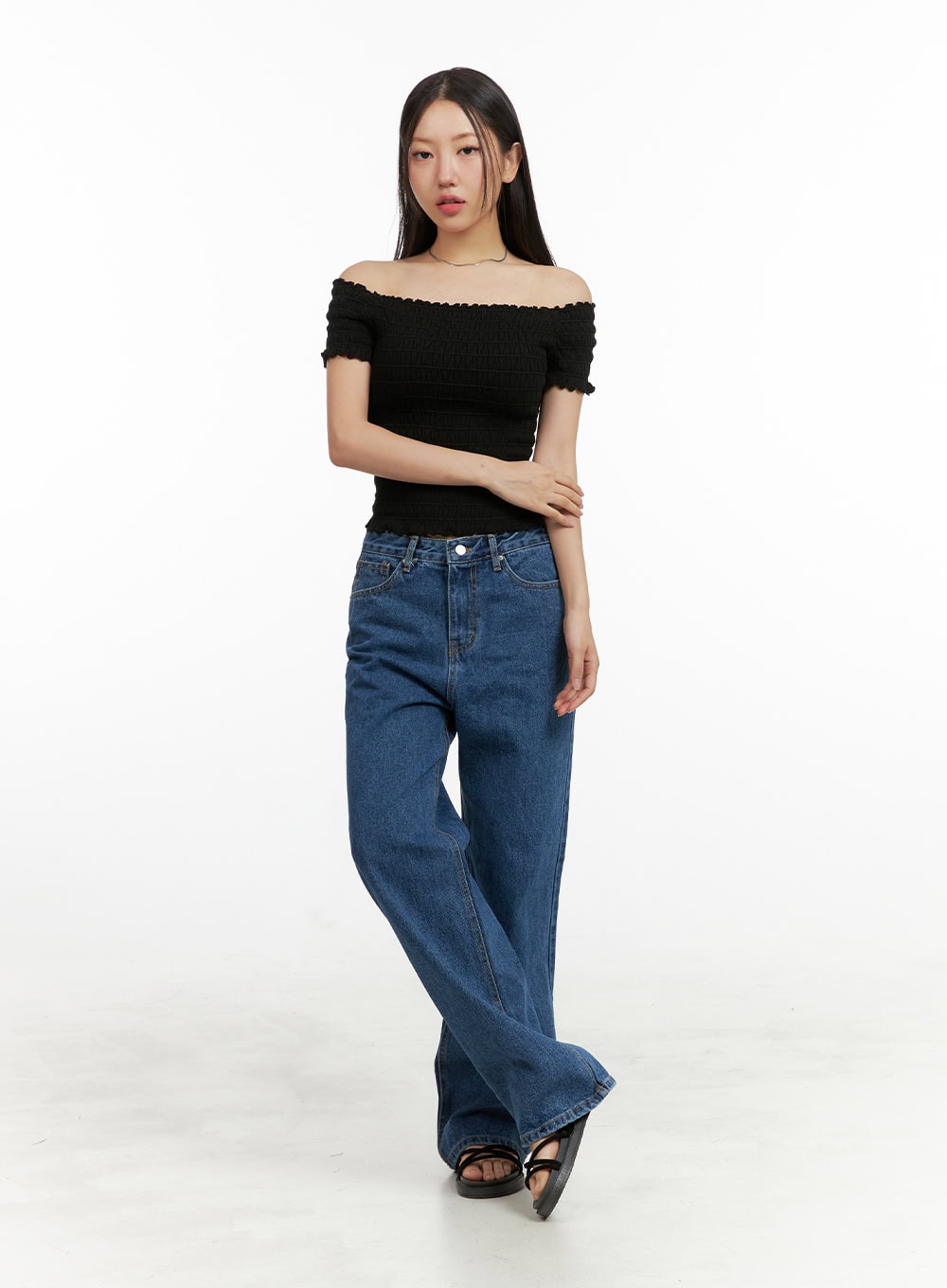 Blue Wide-Leg Jeans OU407 in blue, full-body front view on model, relaxed wide-fit washed cotton denim with high waist, styled with black off-shoulder smocked top and strappy sandals.