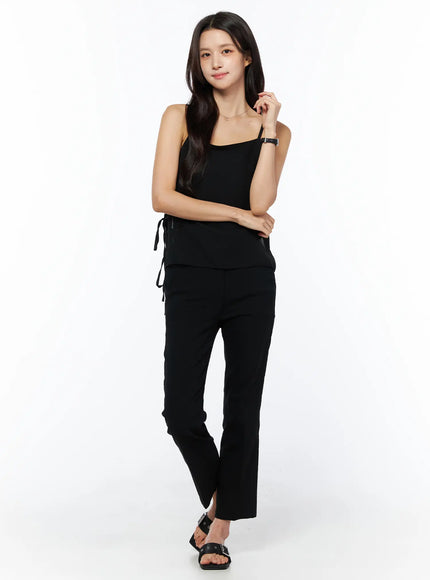 Sheer Ribbon Cami Top CU522 in black, full-body front shot on model, square neckline, thin straps, side ribbon ties, paired with black flare trousers and sandals.