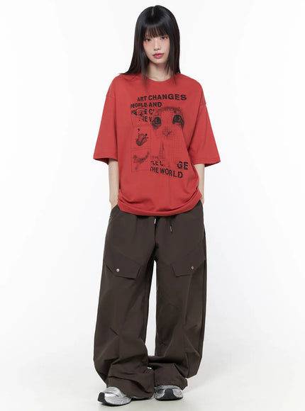 Wide Leg Pintuck Cargo Pants CU519 in dark brown, front full-body on model, wide leg with pintuck seam detailing, paired with red graphic oversized tee and silver sneakers.