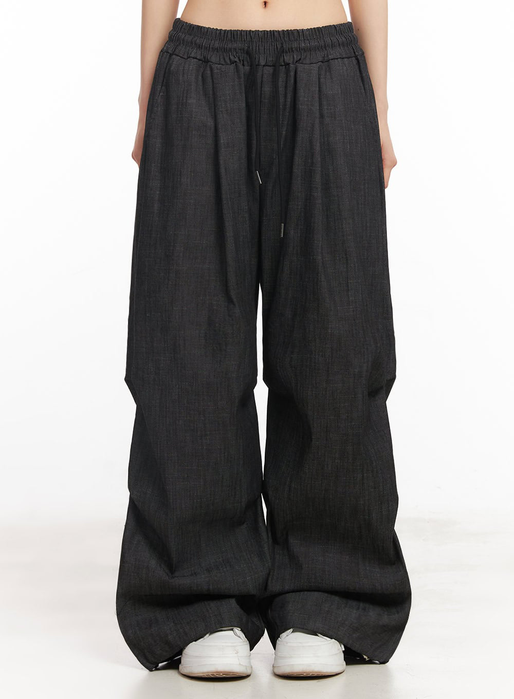 Pintuck Denim Sweatpants IY529 in black, front product shot on model, elastic banded waist with center drawstring, pintuck pleats, wide-fit cotton denim leg pooling at hem, white sneakers.