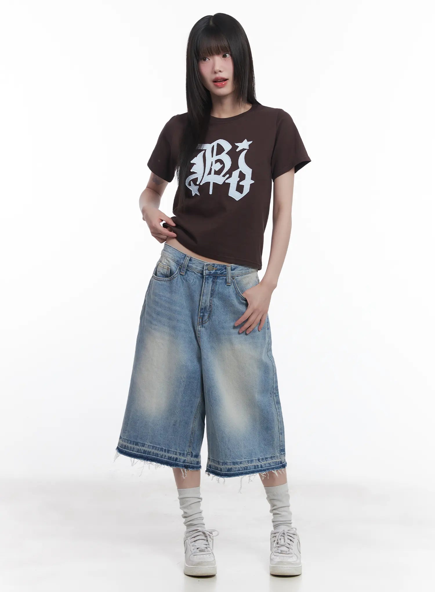 Light Wash Vintage Jorts CU519 in blue, front full-body on model, wide baggy midi jorts with low waist and frayed hem, styled with brown graphic crop tee and chunky white sneakers.