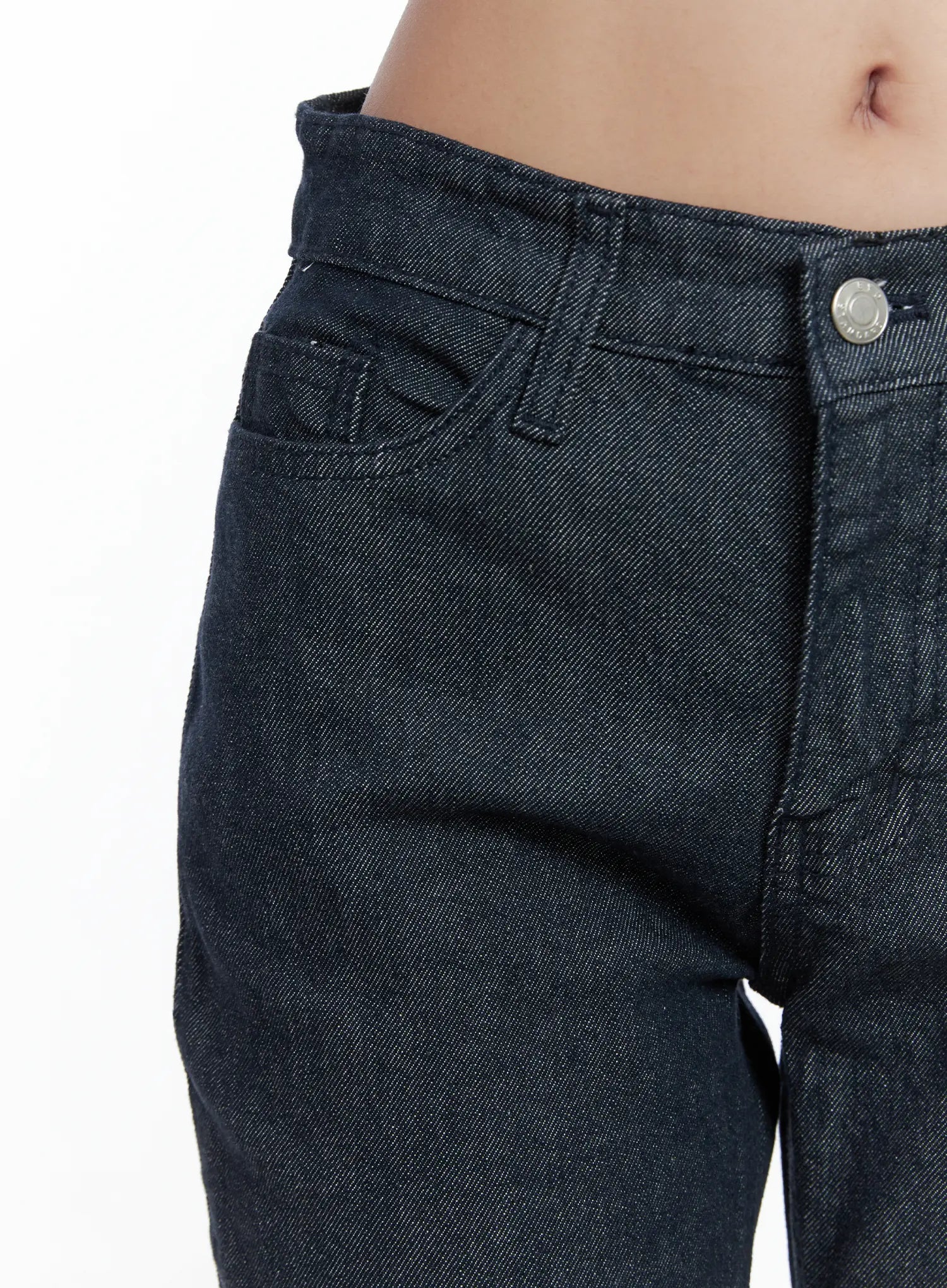 Kinley Flare Jeans CS502 in dark indigo, close-up of waistband and front pocket detail on model, silver button closure, angled coin pocket, mid-rise fit.