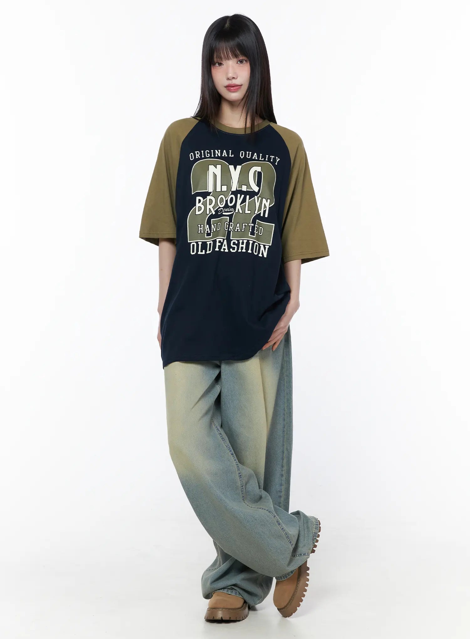 Casual Loose Fit Graphic Tee CU519 in dark blue, full-body front shot on model, olive raglan sleeves, oversized fit with Brooklyn NYC graphic, paired with wide-leg faded jeans and chunky shoes.
