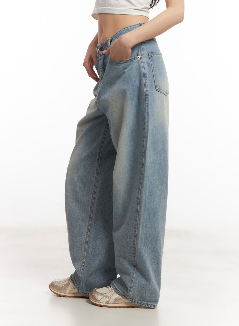 Devyn Wide-Leg Jeans CA503 in blue, side view on model, washed cotton denim showing wide-leg volume and low-rise waist, hand in back pocket, white crop top.
