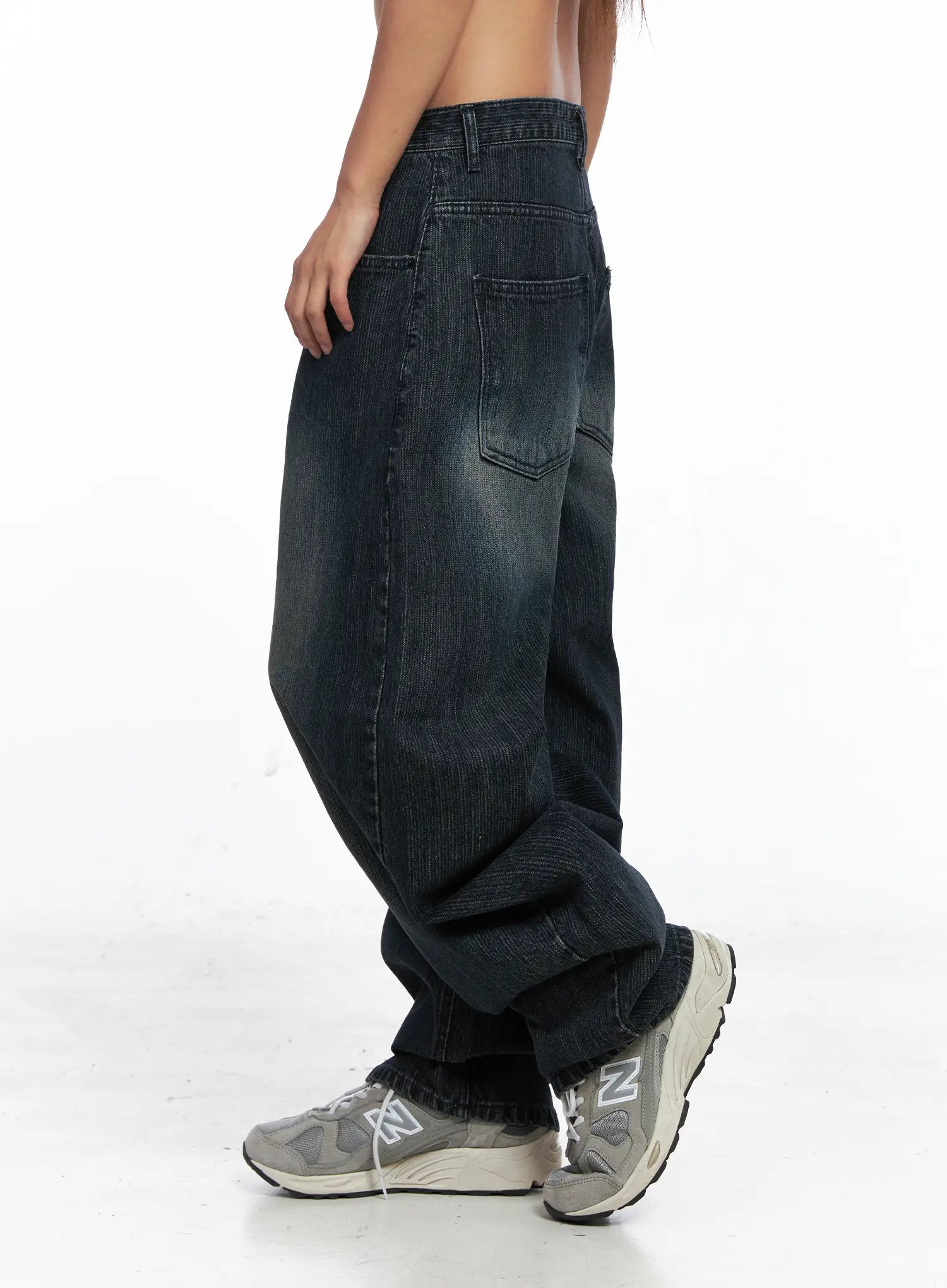 Aspyn Wide-Leg Washed Corduroy Jeans CO510 in dark blue, side view on model, back pocket and wide-leg silhouette visible, washed corduroy texture, hem bunching over New Balance sneakers.
