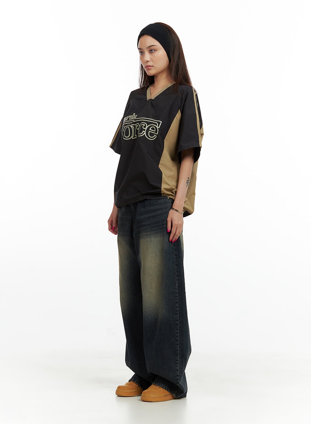 Solid Low Rise Baggy Jeans CU417 in dark blue, side view on model, low-rise baggy washed denim with ultra-wide leg and yellow whisker fade, styled with sporty black and tan jersey.