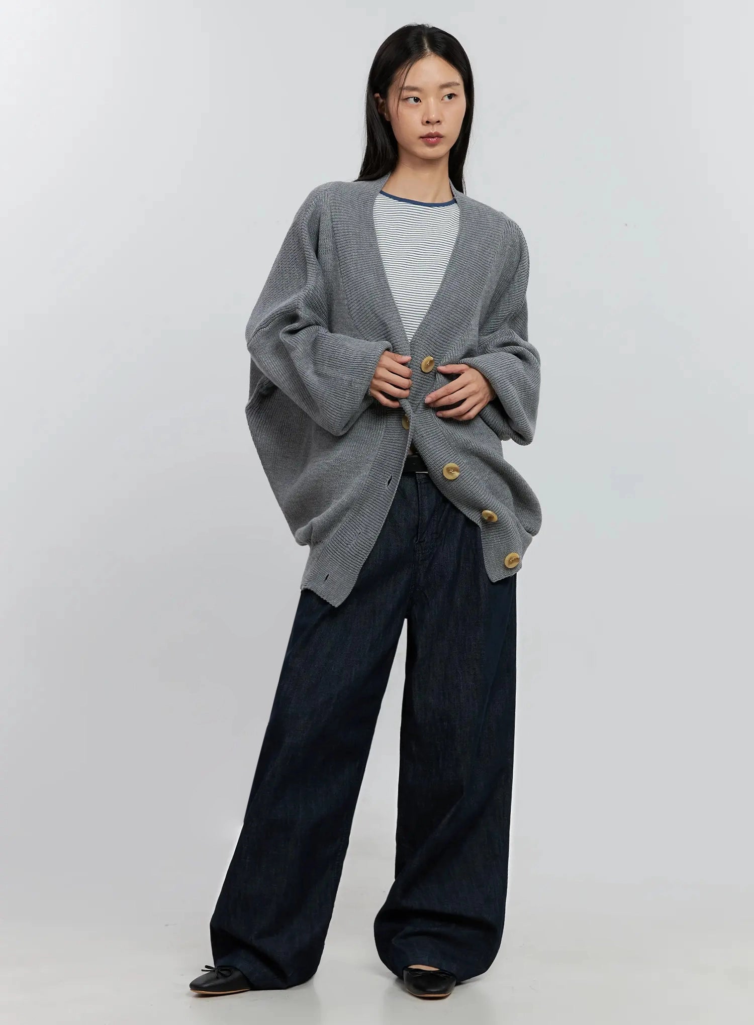 Elio Pintuck Wide-Leg Jeans IS516 in dark indigo, front full-body on model, low-rise waistband with silver button, ultra-wide leg silhouette, paired with oversized grey knit cardigan.