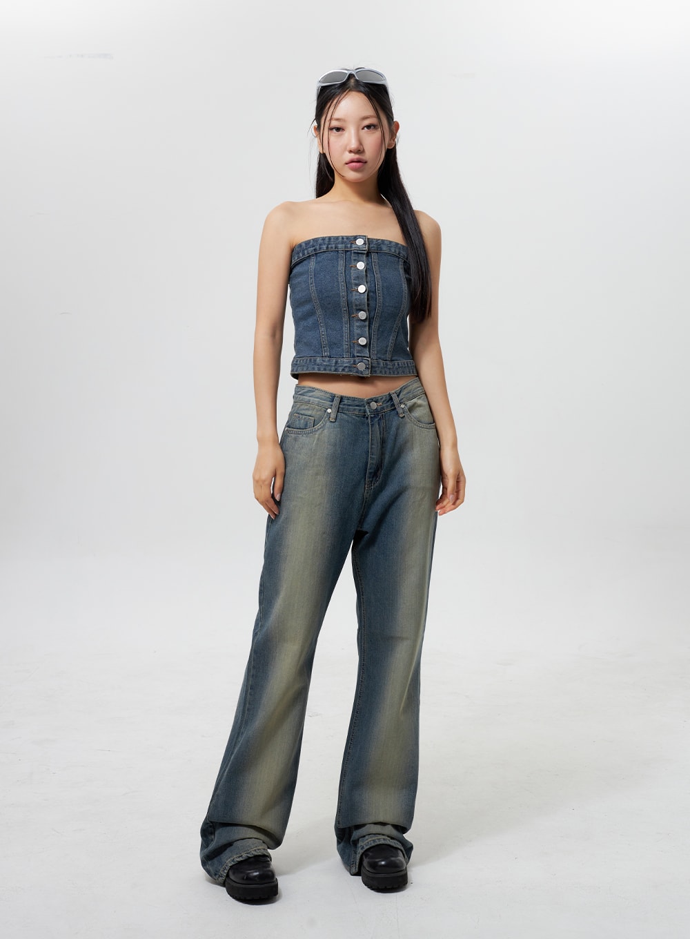 Low Rise Wide Leg Jeans CY323 in vintage blue, full front view on model standing, low-rise fit with wide-leg silhouette, yellow-tinted faded wash, styled with denim bandeau top and chunky boots.