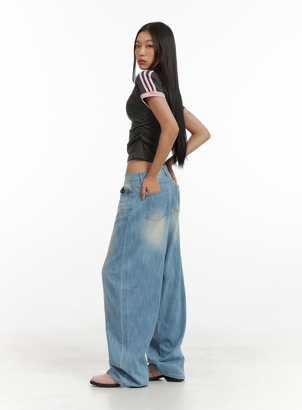 Washed Comfort Baggy Jeans CU414 in light blue, side view on model looking back, showing voluminous wide leg and back pocket, paired with dark crop tee.